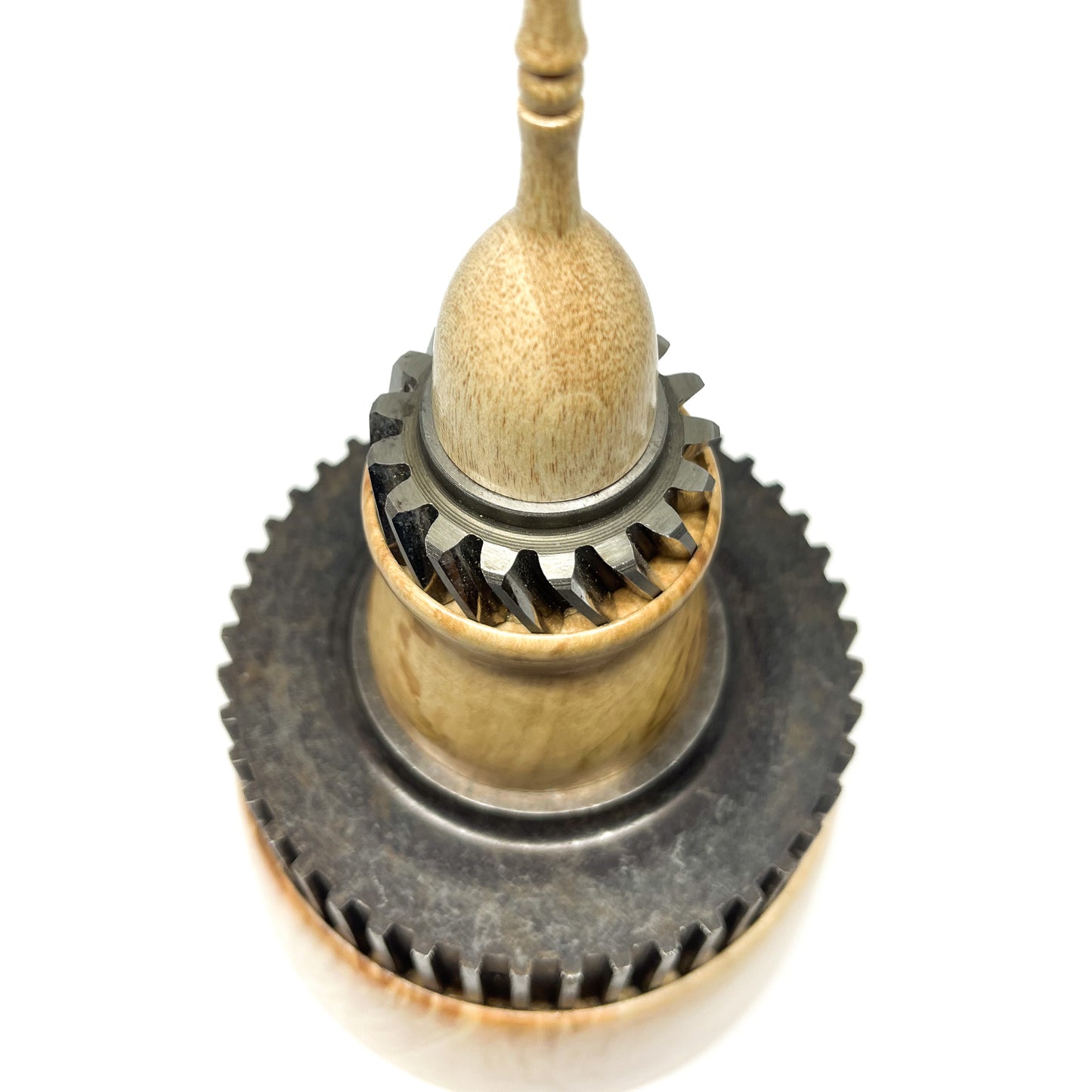 Close-up overhead view of a stacked wood spire sculpture by David Adolph with two dark cog-like rings and slender top.