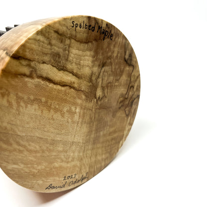 Close-up of the textured wood base of a sculpture signed "Spalted Maple 2023 David Adolph".