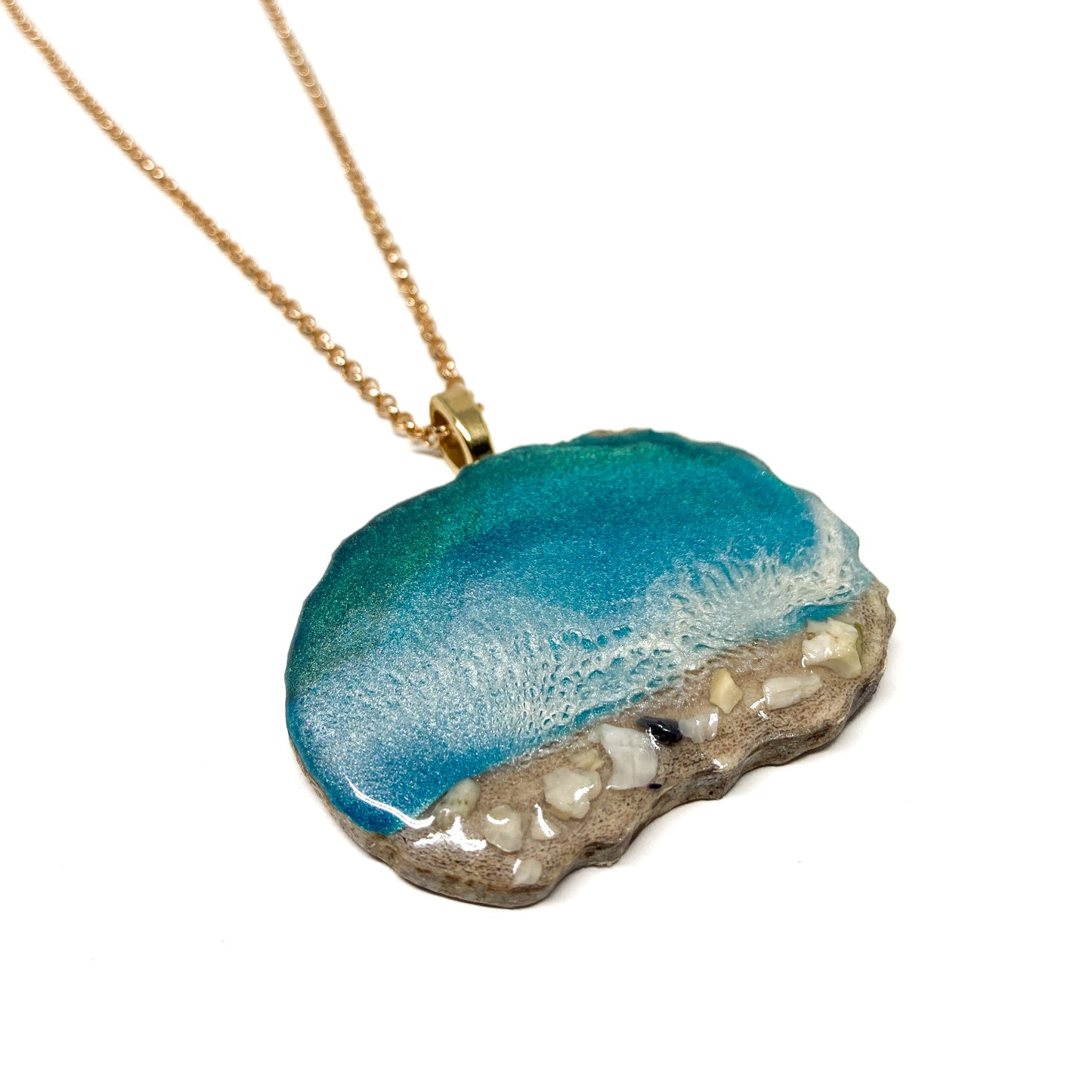 A necklace with an ocean-inspired pendant, featuring blue resin and sand-like textures.