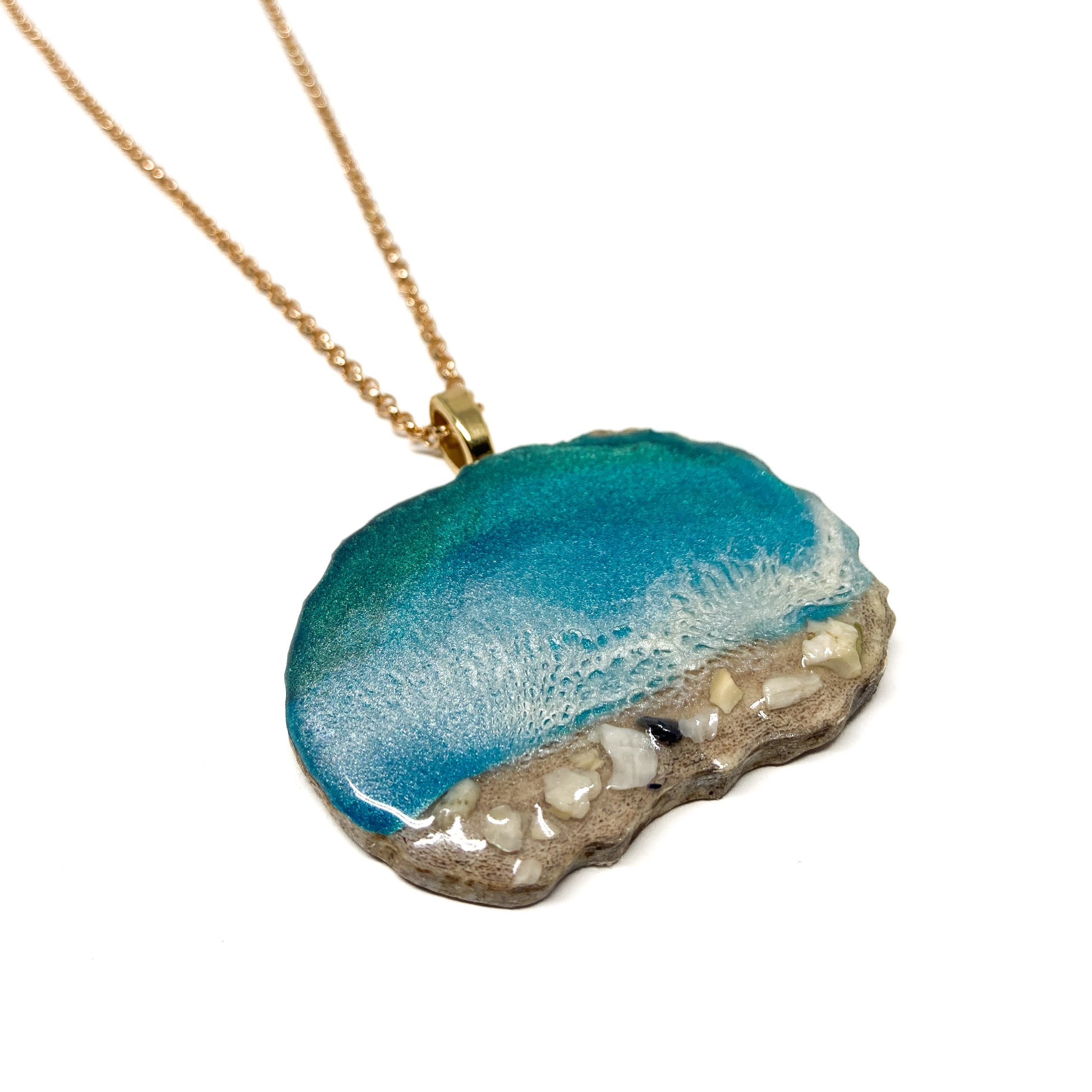A necklace with an ocean-inspired pendant, featuring blue resin and sand-like textures.