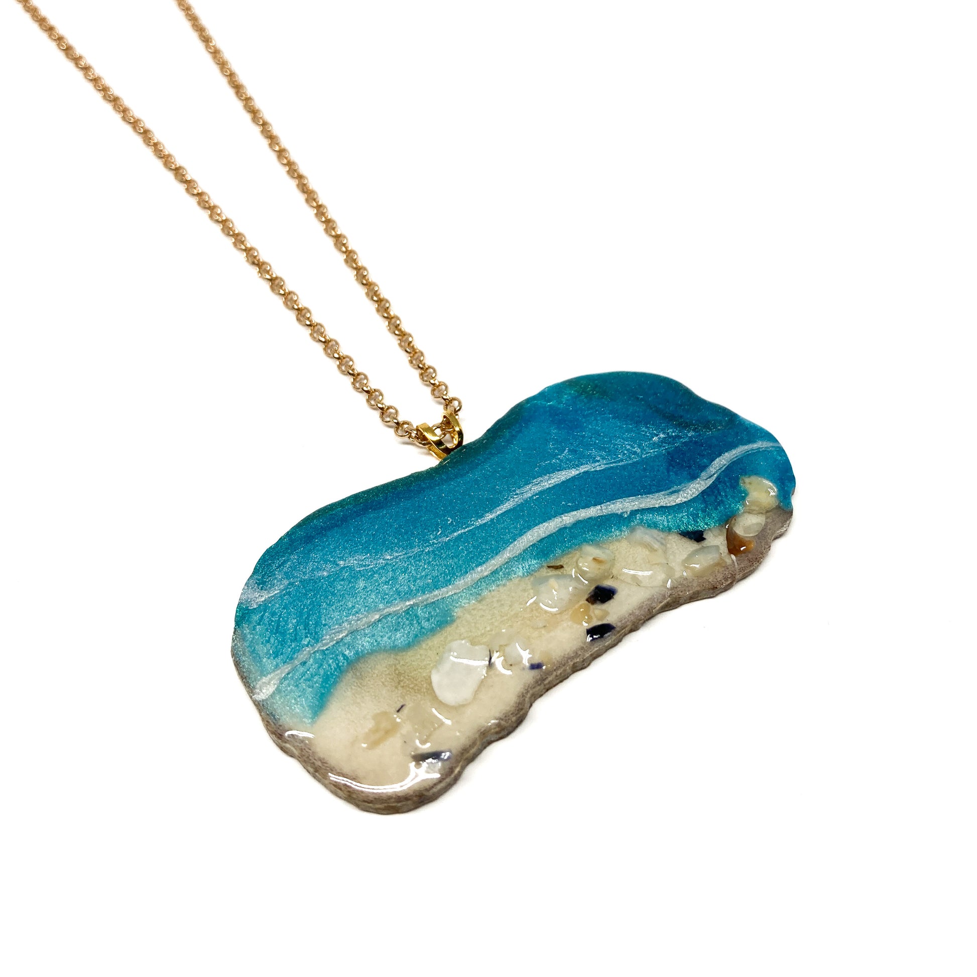 A necklace with an ocean-inspired pendant, featuring blue resin and sand-like textures.