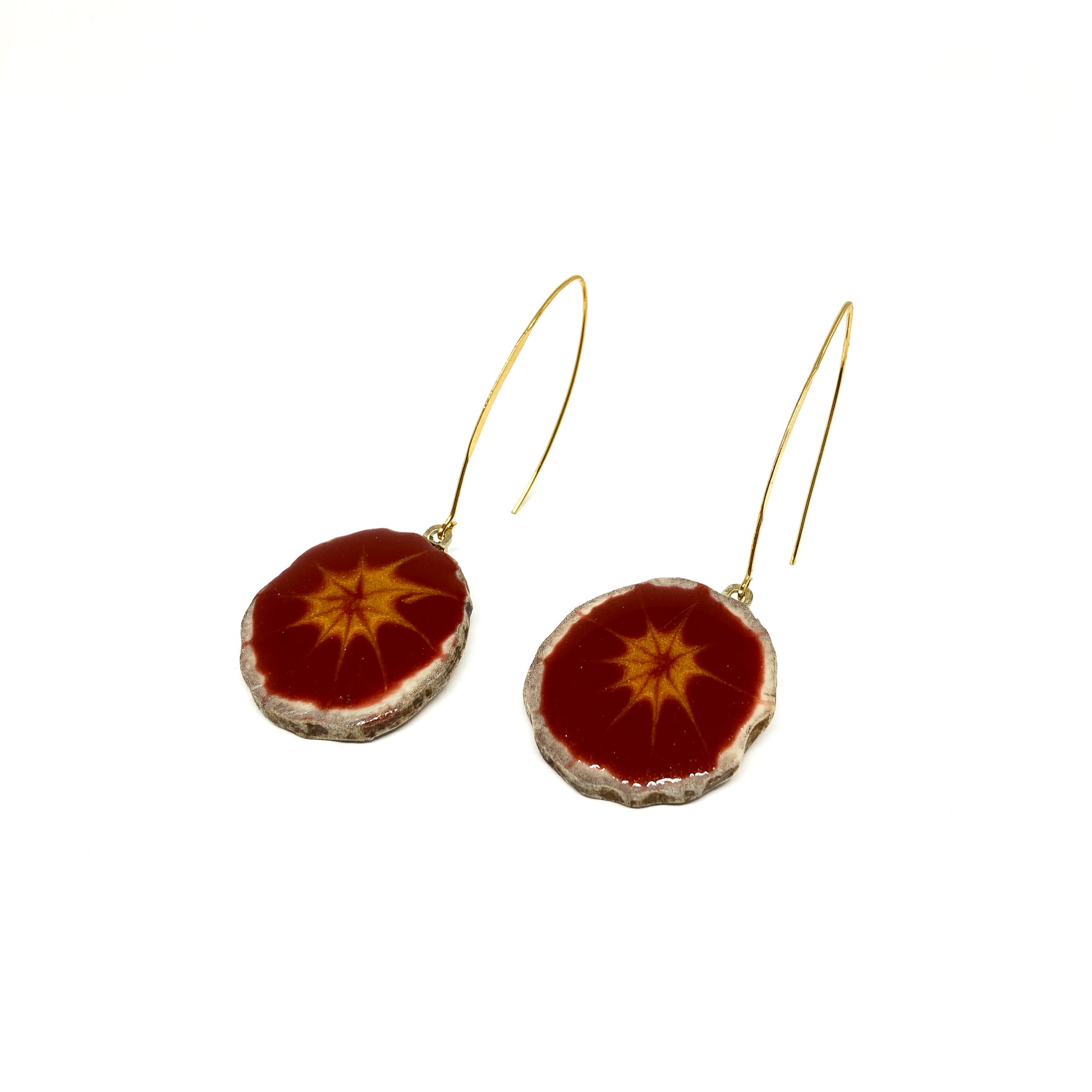 Two round earrings with red and gray starburst patterns, featuring gold hooks.
