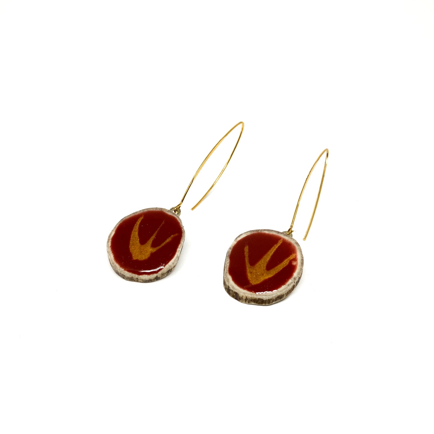 Two round earrings with red and gold bird-shaped designs, featuring gold hooks.
