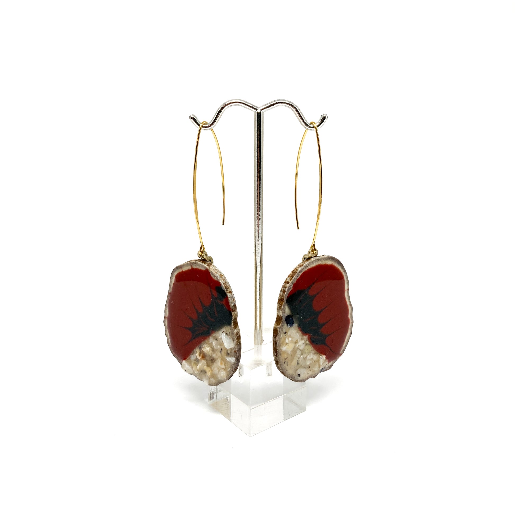Two round earrings with red and black bird-shaped designs, displayed on a silver earring stand.