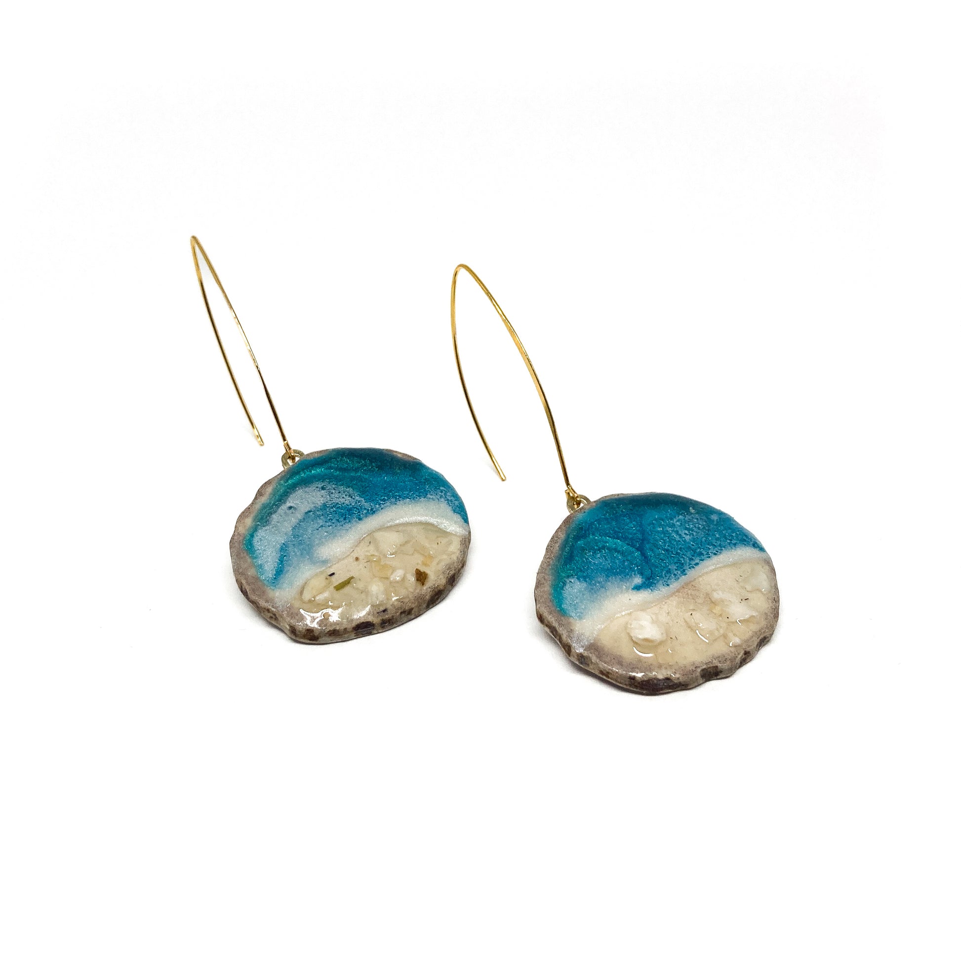 Two round earrings with blue and white geode-like designs, featuring gold hooks.