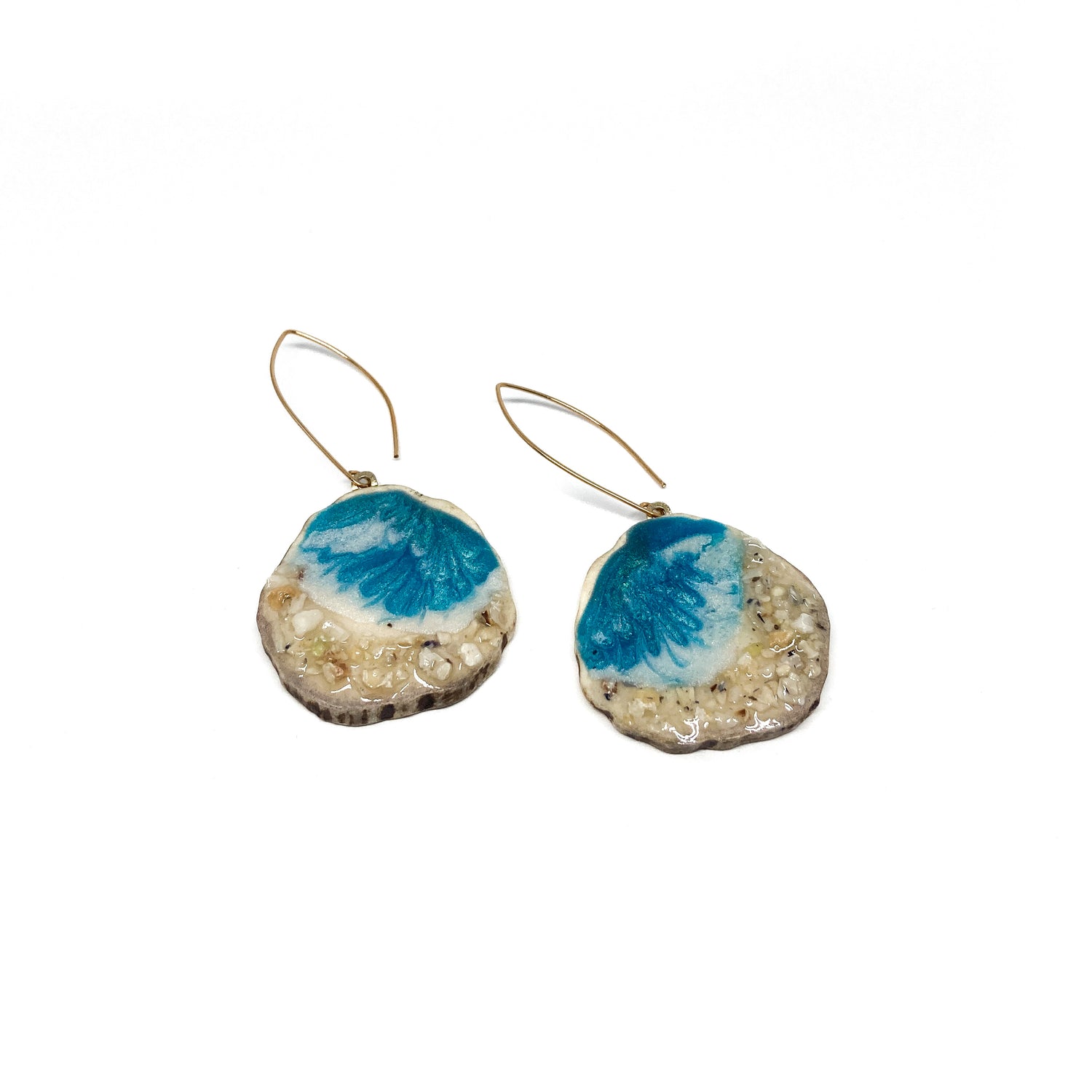 Two round earrings with blue and white geode-like designs, featuring gold hooks.