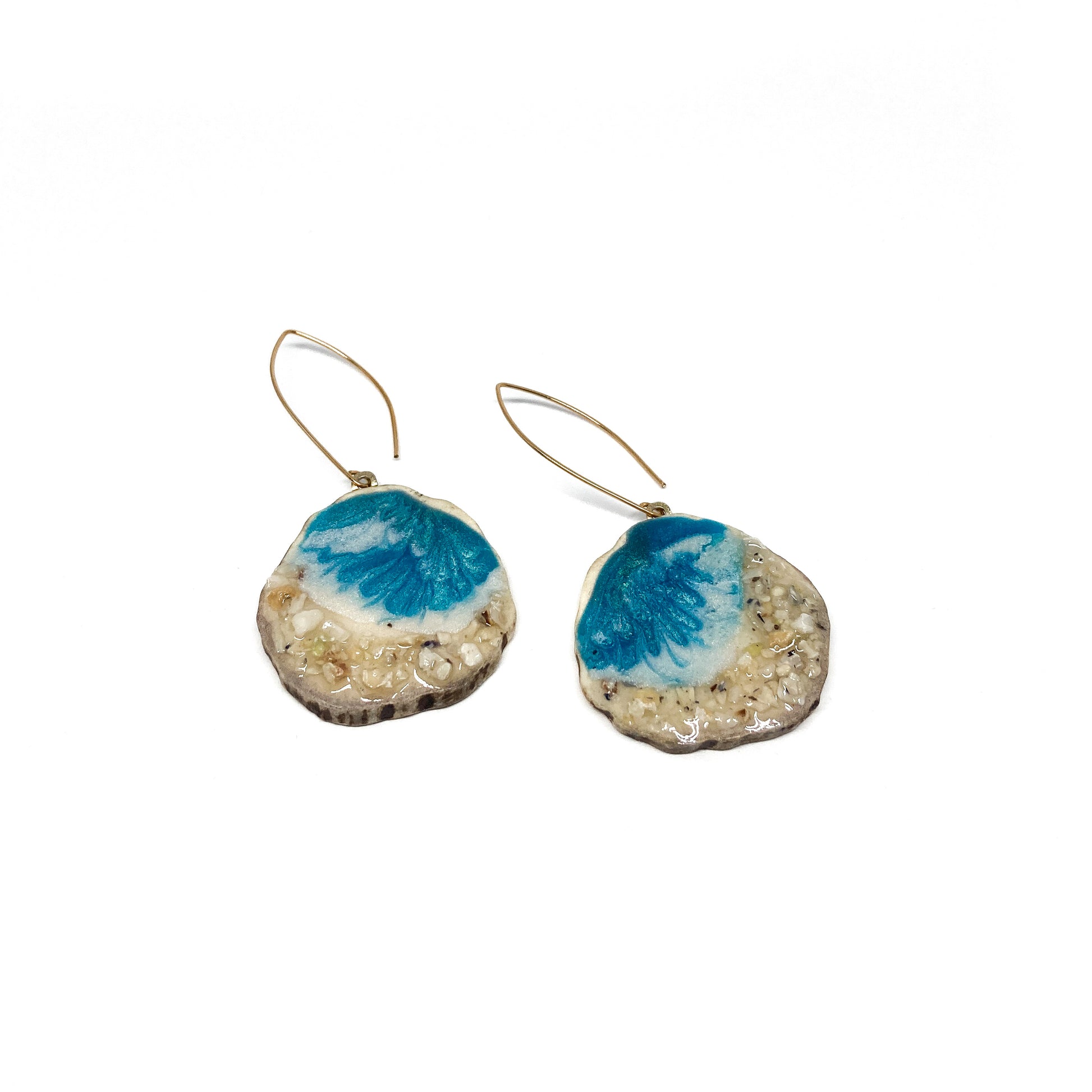 Two round earrings with blue and white geode-like designs, featuring gold hooks.
