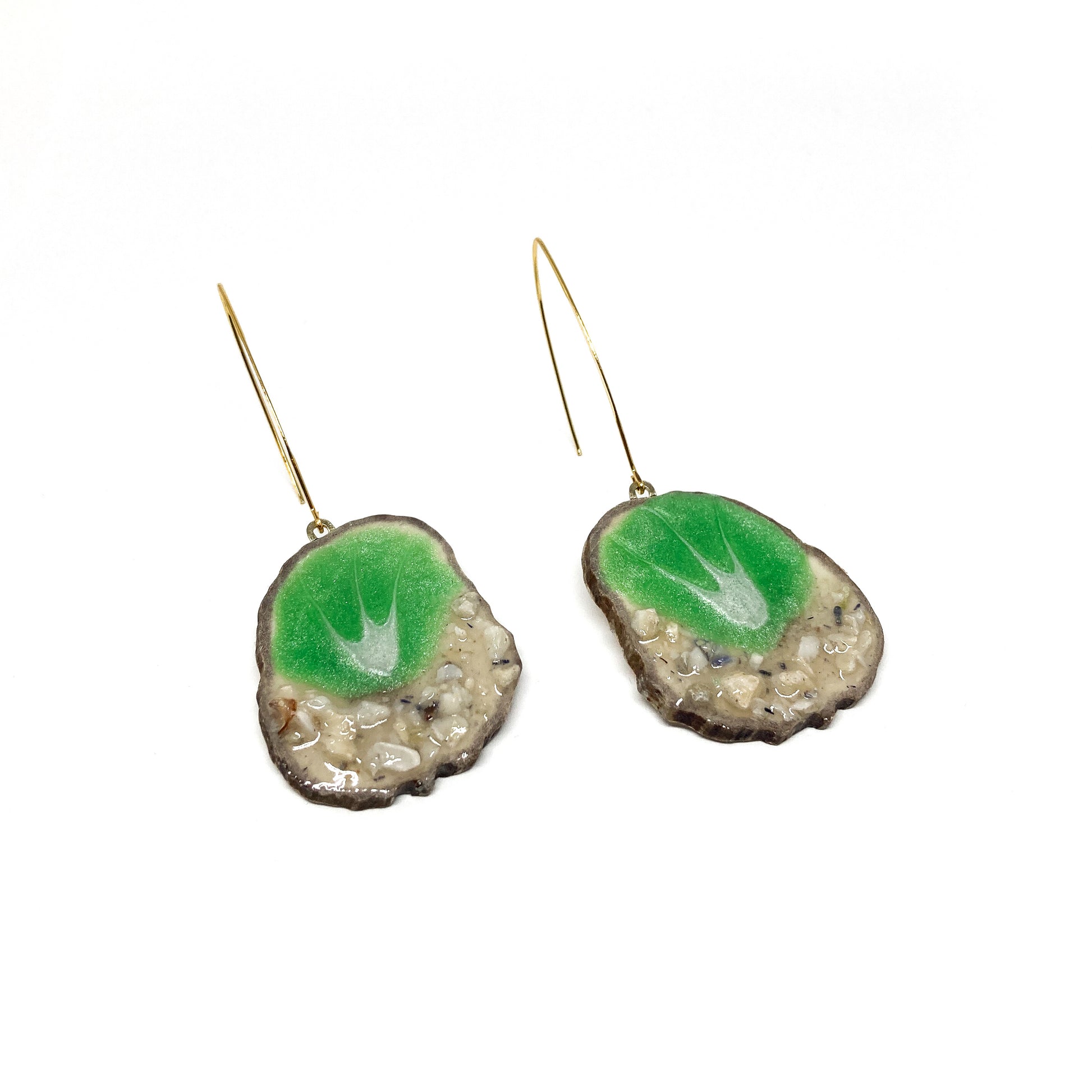 Two round earrings with green and white leaf-shaped designs, featuring gold hooks.
