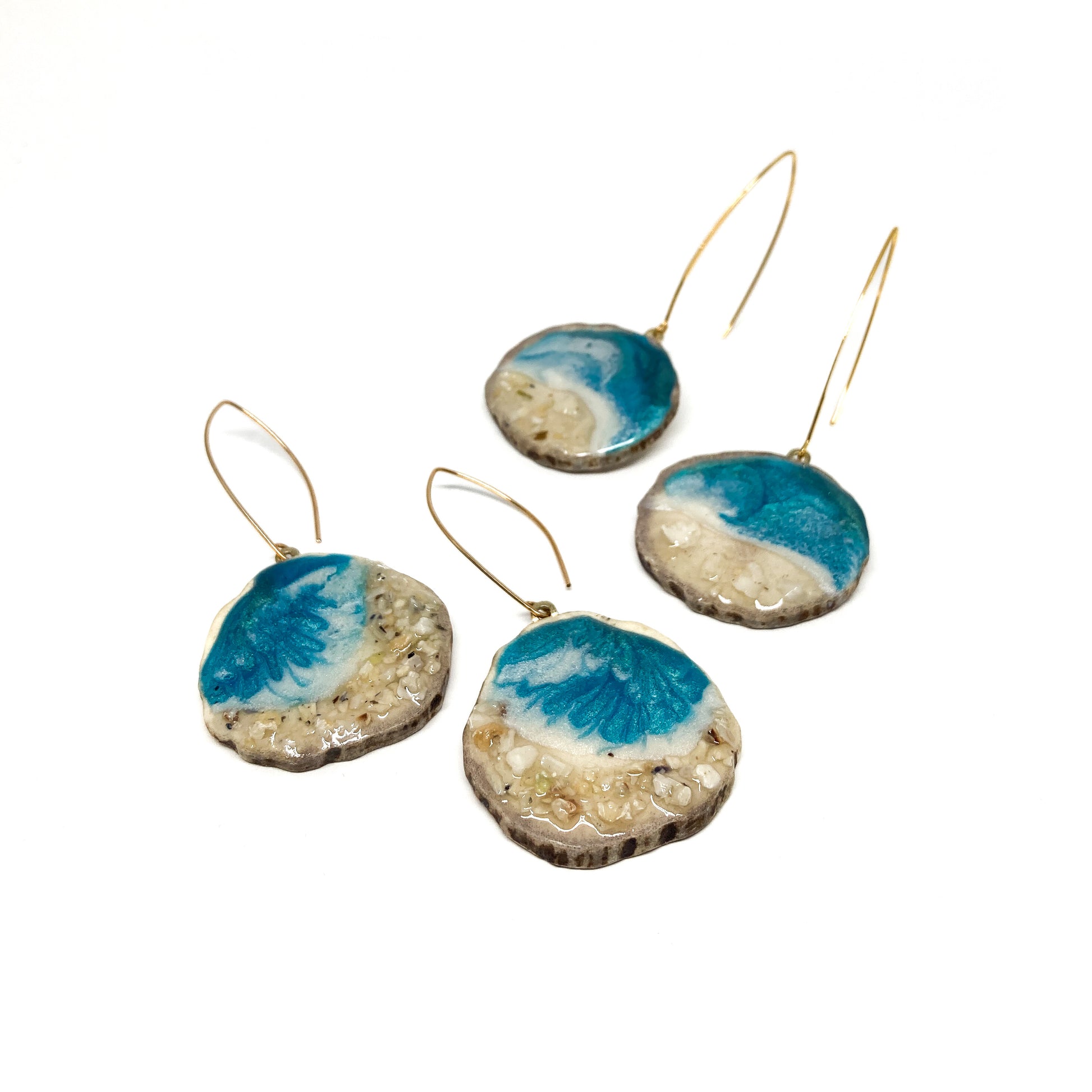 Four round earrings with blue and white geode-like designs, featuring gold hooks.