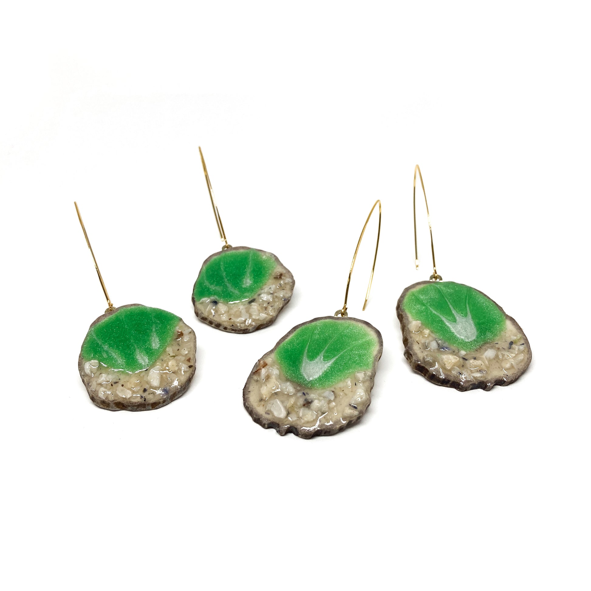 Four round earrings with green leaf-shaped designs, featuring gold hooks.