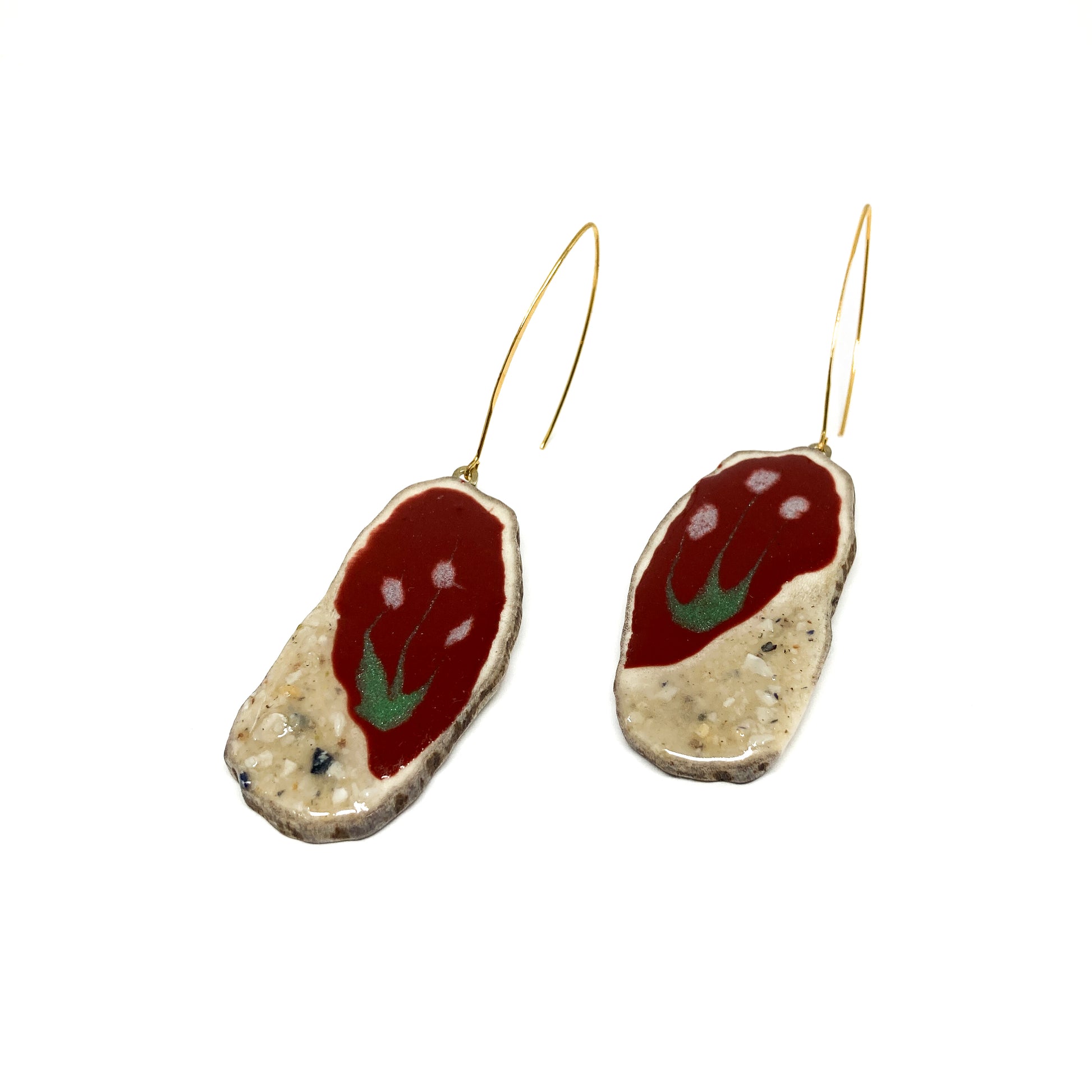 Two round earrings with red and white flower-like designs, featuring gold hooks.