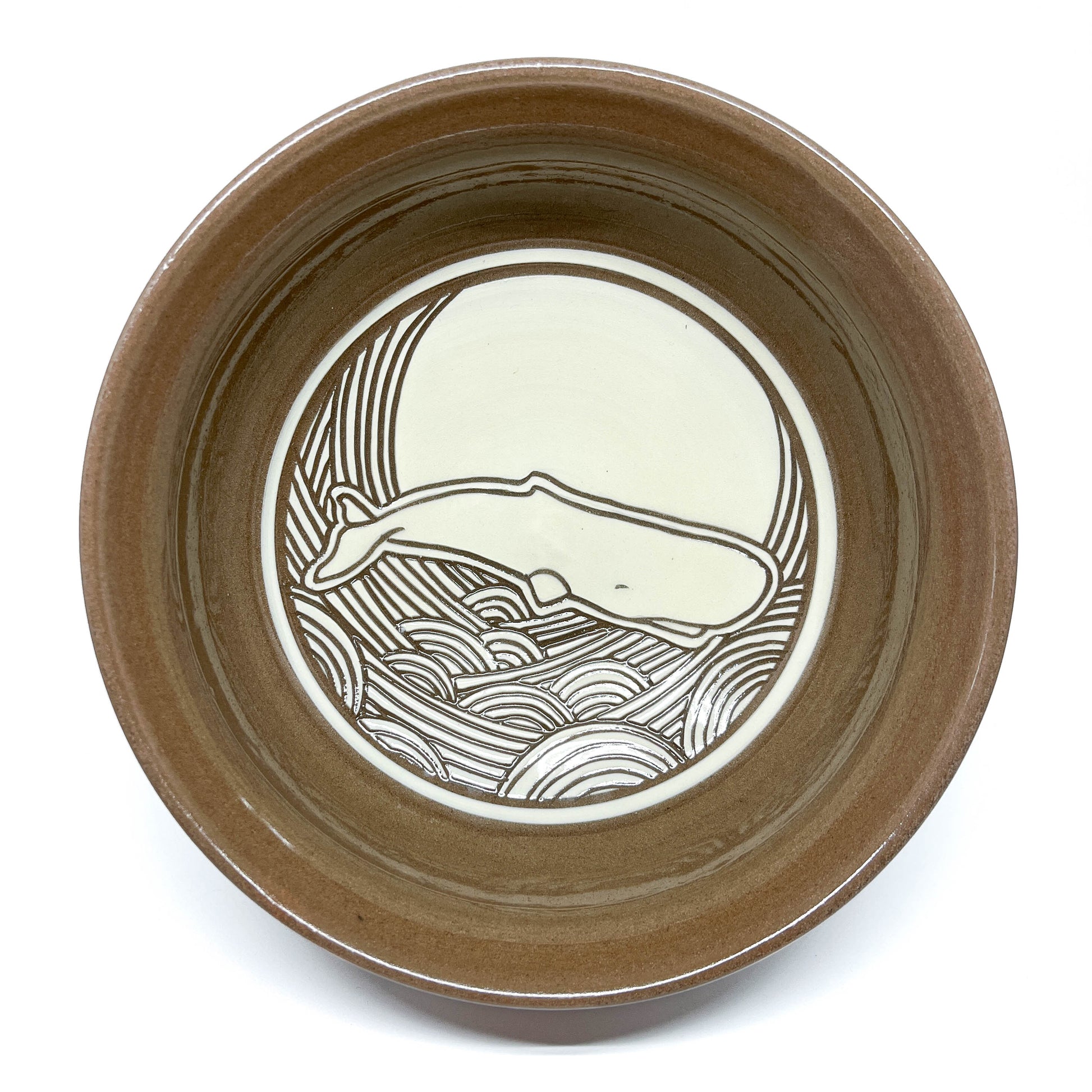 Top view of a ceramic bowl with an orca illustration set against a sun and swirling ocean design.