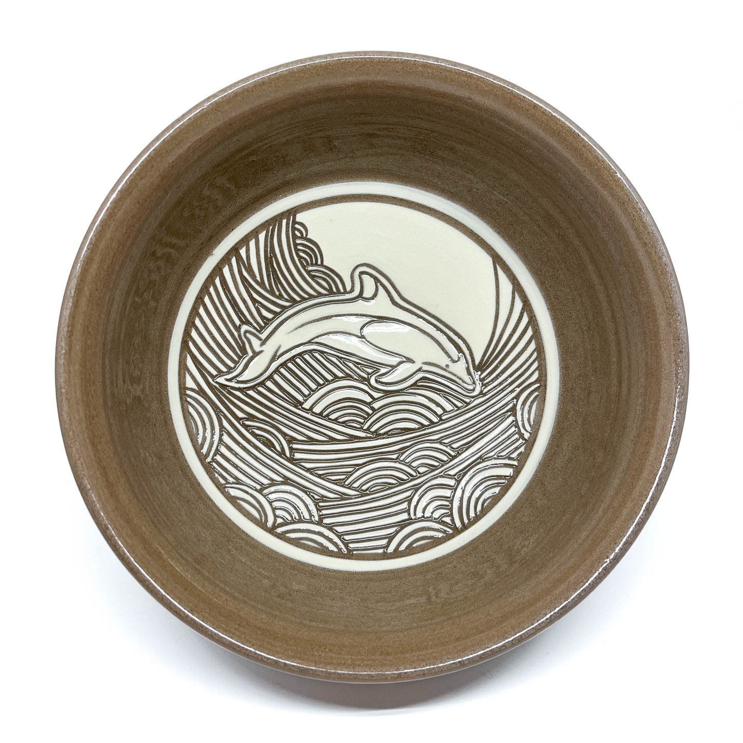 Top-down view of a bowl with whale carving and detailed wave background, moon visible above.