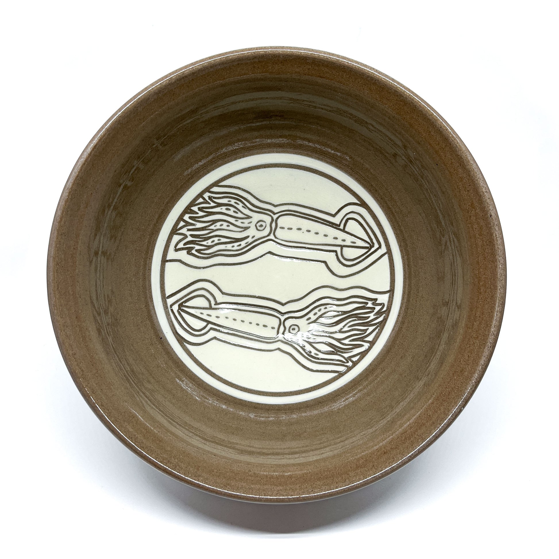 Top view of a ceramic bowl featuring two intricately carved squids facing opposite directions inside a circular frame.
