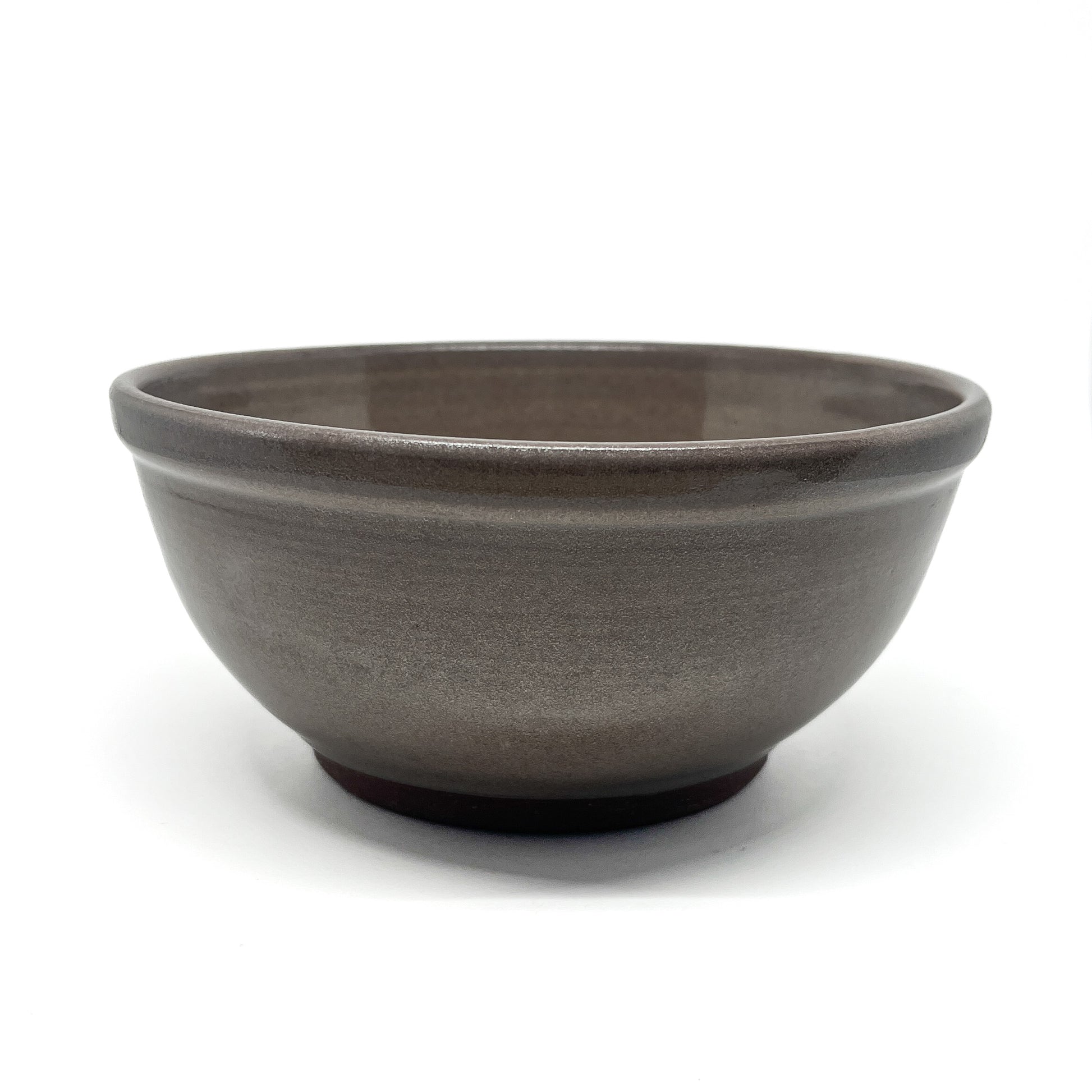 Side view of a footed ceramic bowl with a smooth, glazed exterior and a gently rounded rim.