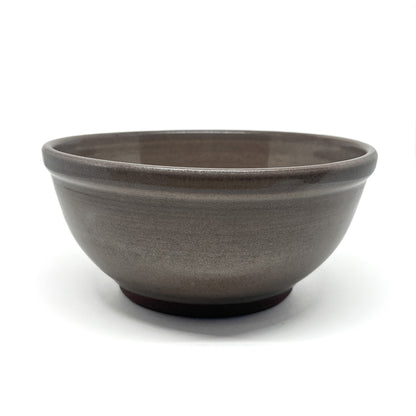 Side view of a footed ceramic bowl with a smooth, glazed exterior and a gently rounded rim.