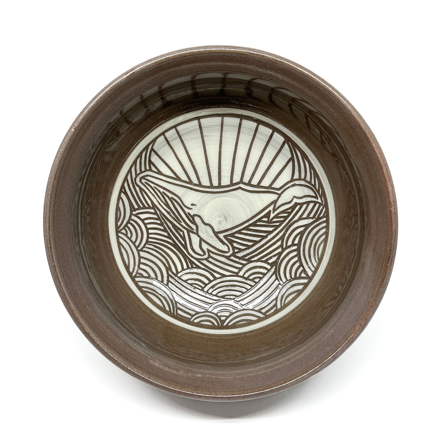 Ceramic bowl featuring an etched whale design surrounded by stylized waves and radiating lines.