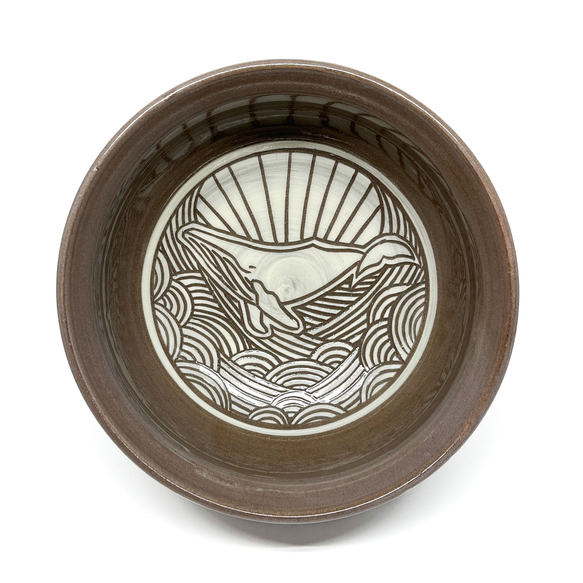Ceramic bowl featuring an etched whale design surrounded by stylized waves and radiating lines.