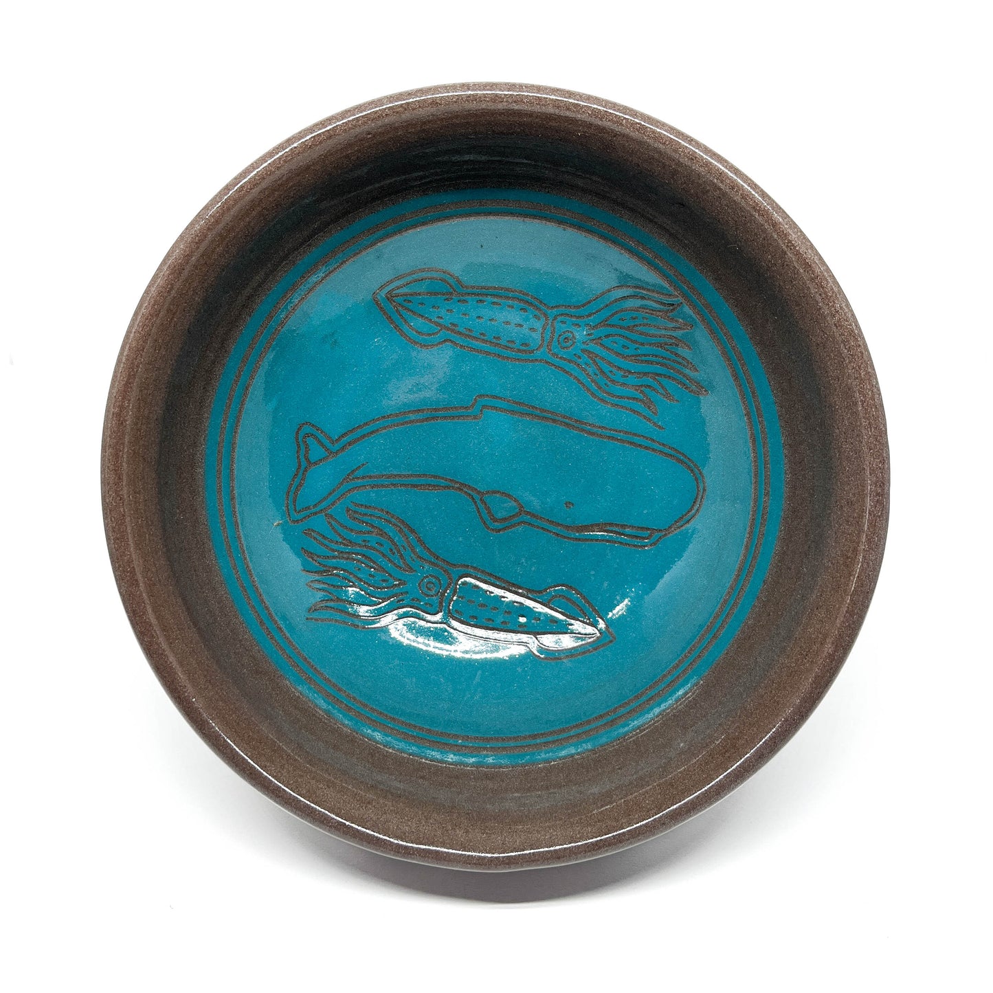Ceramic bowl featuring etched designs of a whale surrounded by two squid in a circular underwater scene.