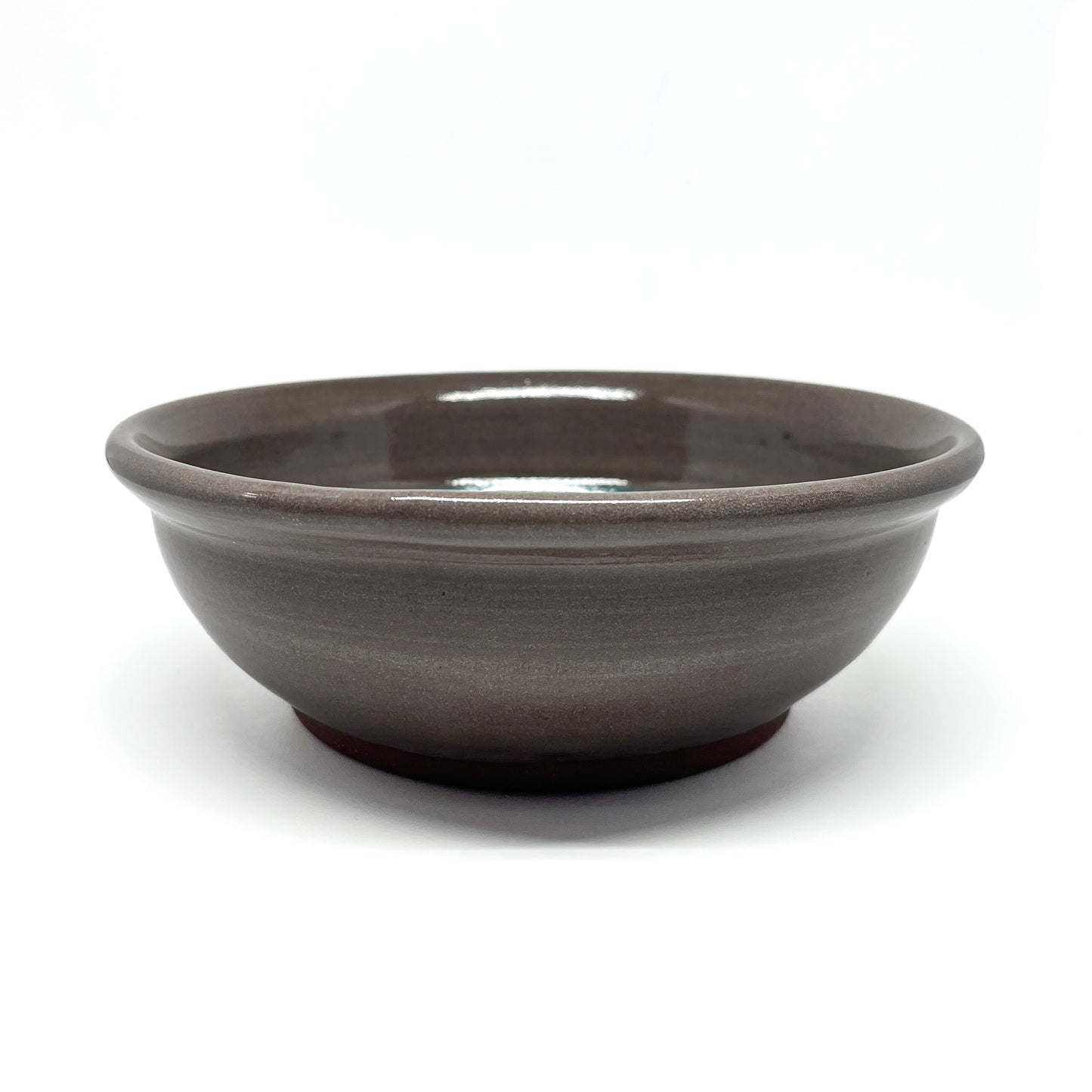Low-profile ceramic bowl with a wide rim and smooth, glossy finish shown from a side angle.