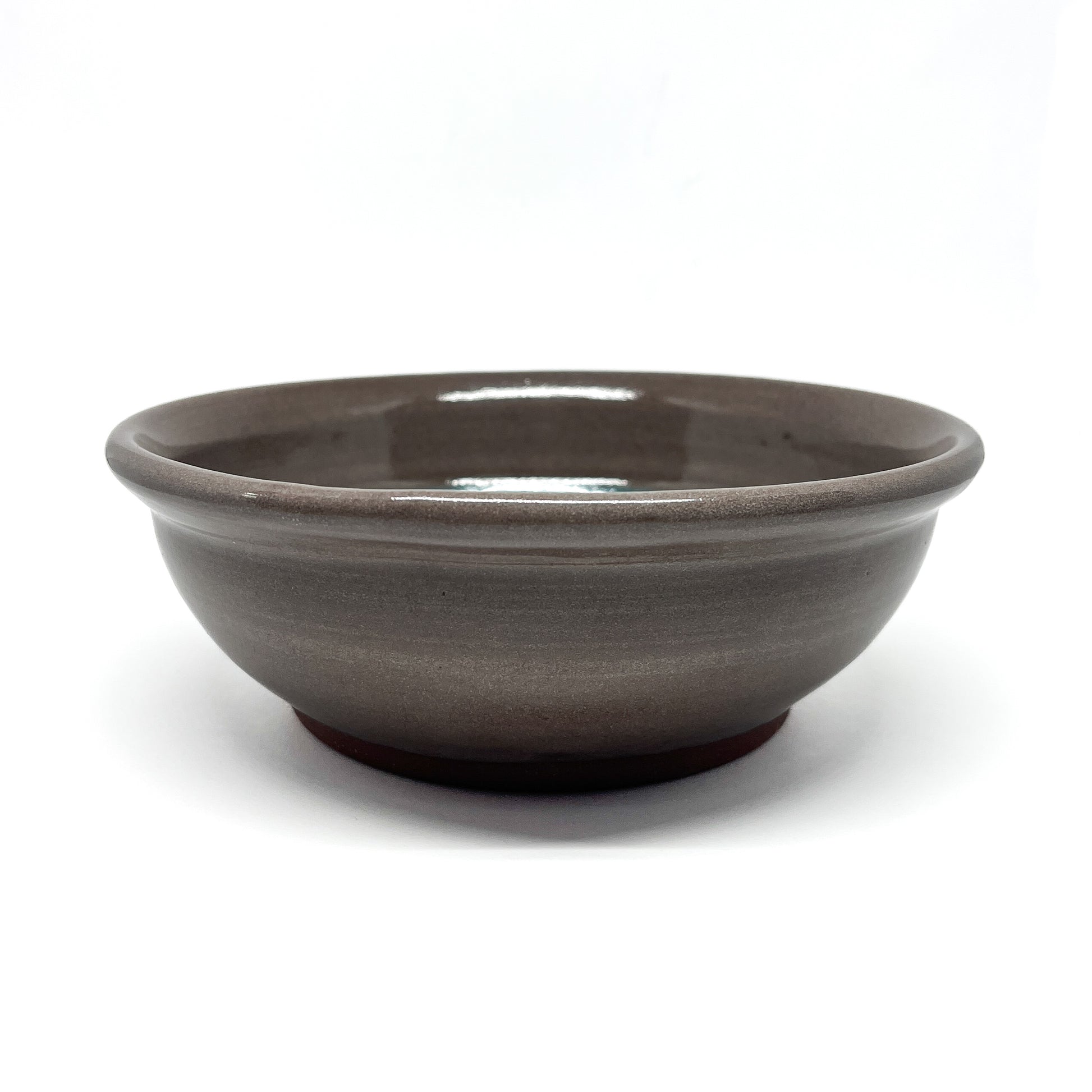 Low-profile ceramic bowl with a wide rim and smooth, glossy finish shown from a side angle.