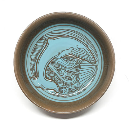 Top view of a bowl with a detailed octopus carving, framed by dynamic wave and sunburst lines.