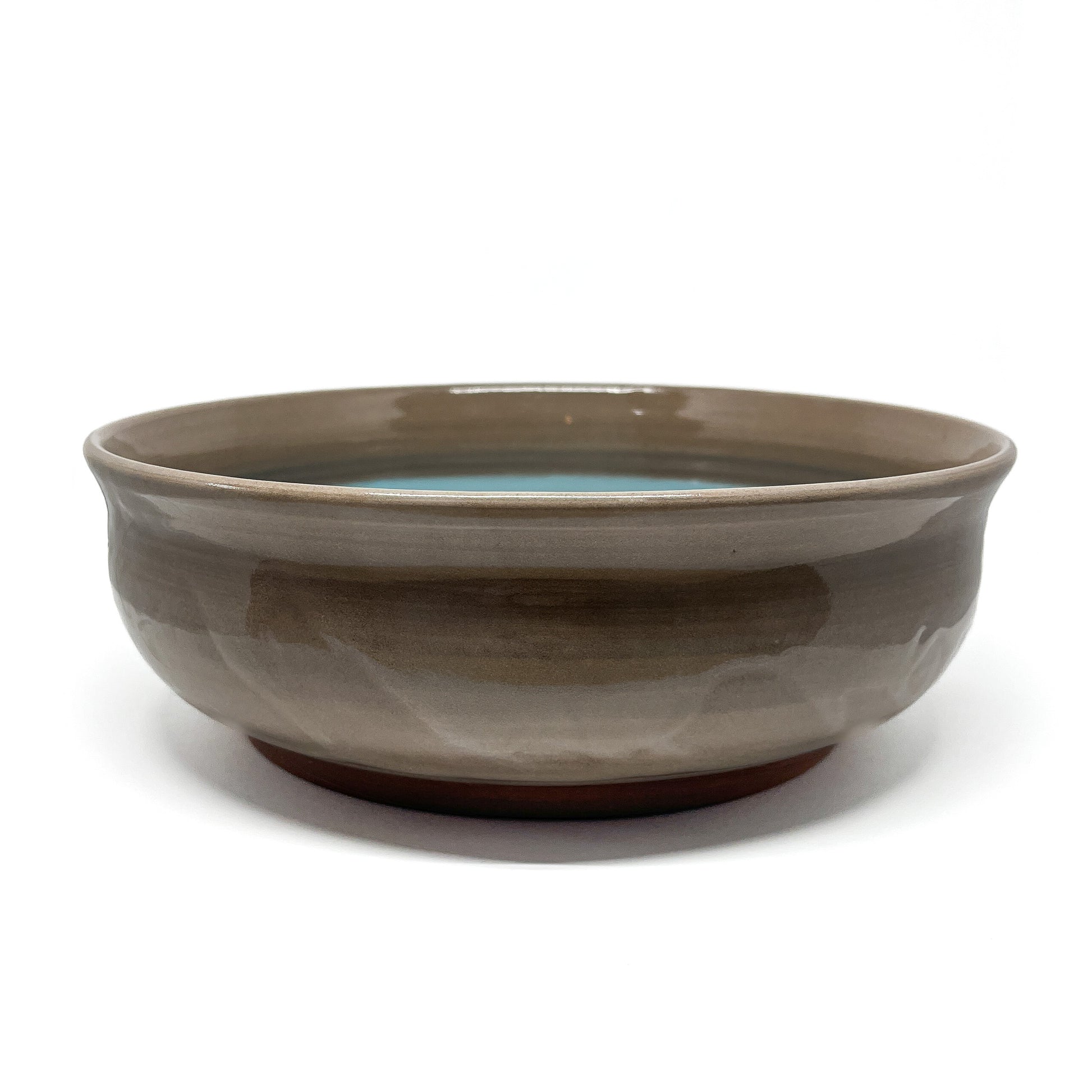 Bottom of a ceramic bowl with a carved whale and wave motif etched into the unglazed base.