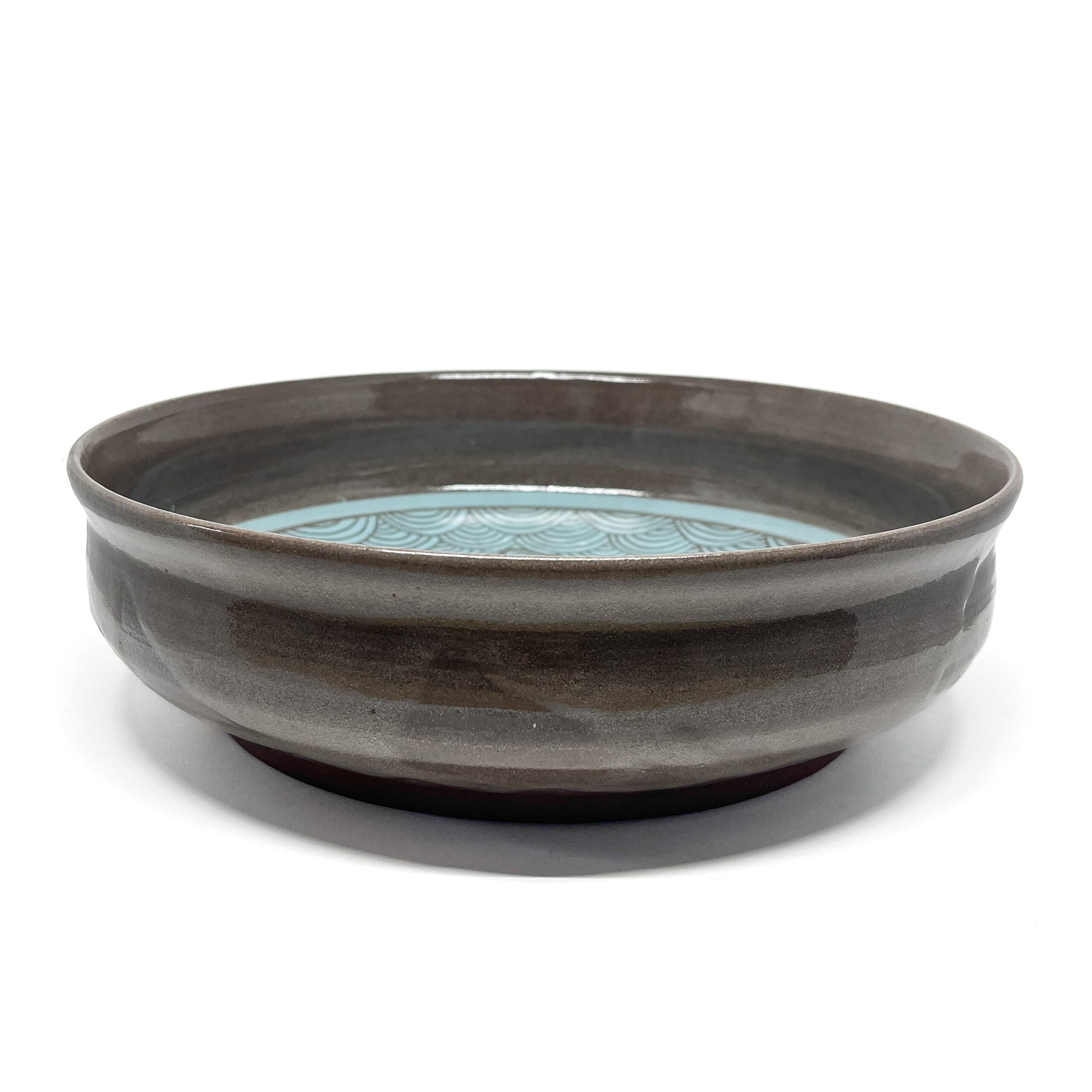 Underside of a ceramic bowl showing unglazed reddish-brown base with no visible design.