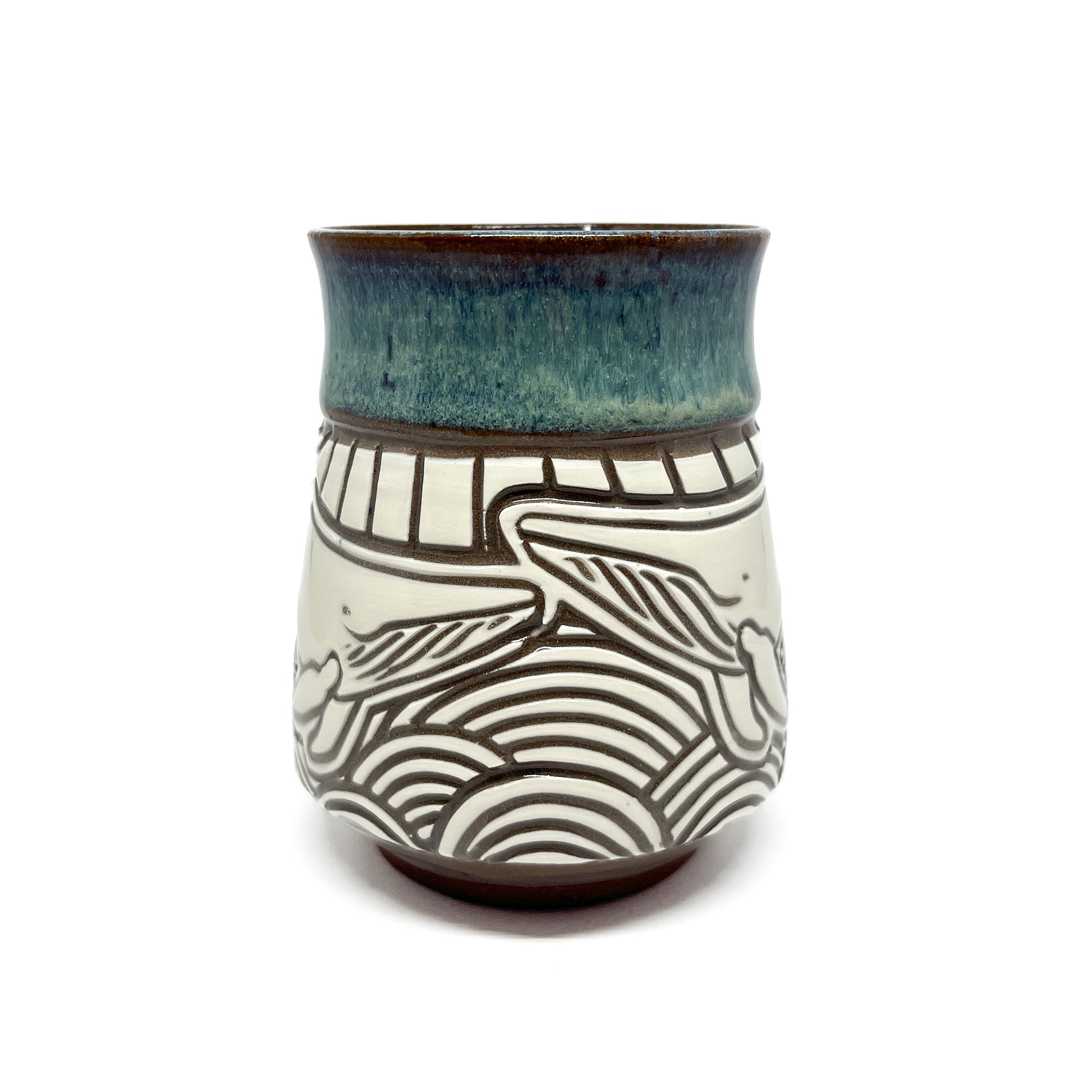 Ceramic mug with carved orca swimming in stylized waves, handle partially visible on the right.