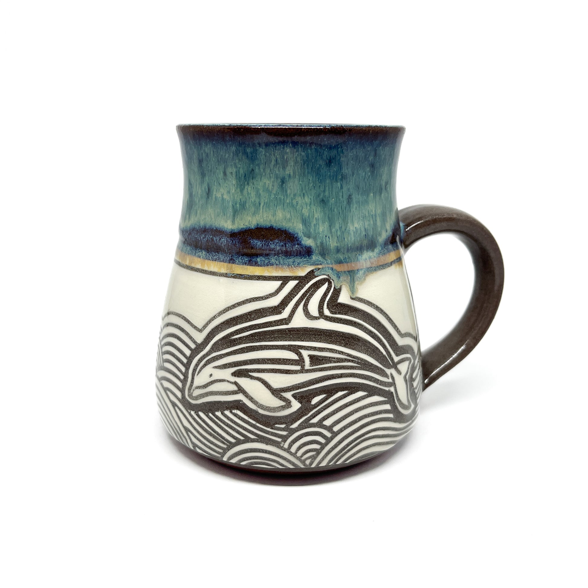 Ceramic mug featuring a carved dolphin design jumping through stylized ocean waves, with glazed rim and handle.