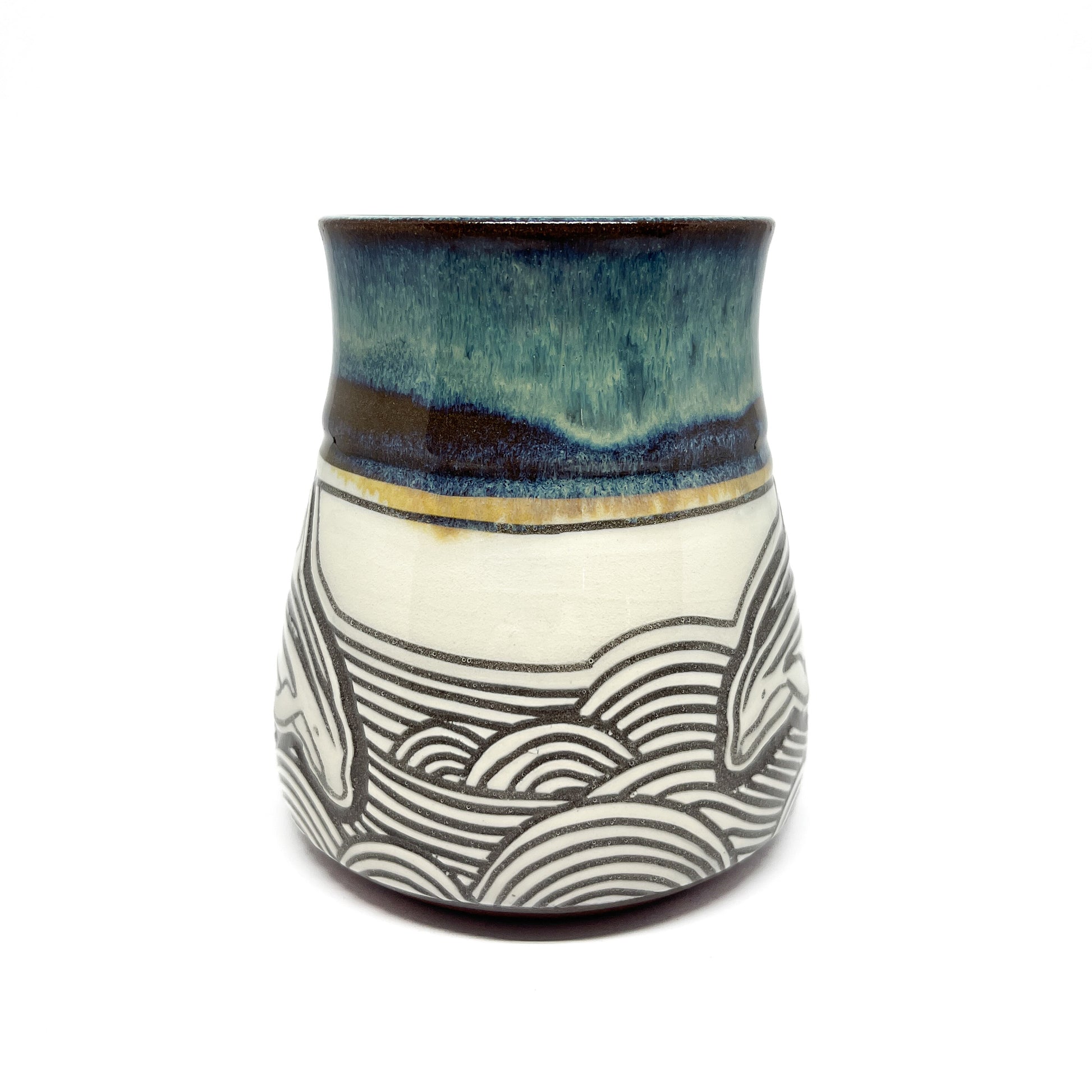 Mug with two carved orcas swimming in parallel through layered wave patterns, side handle visible.