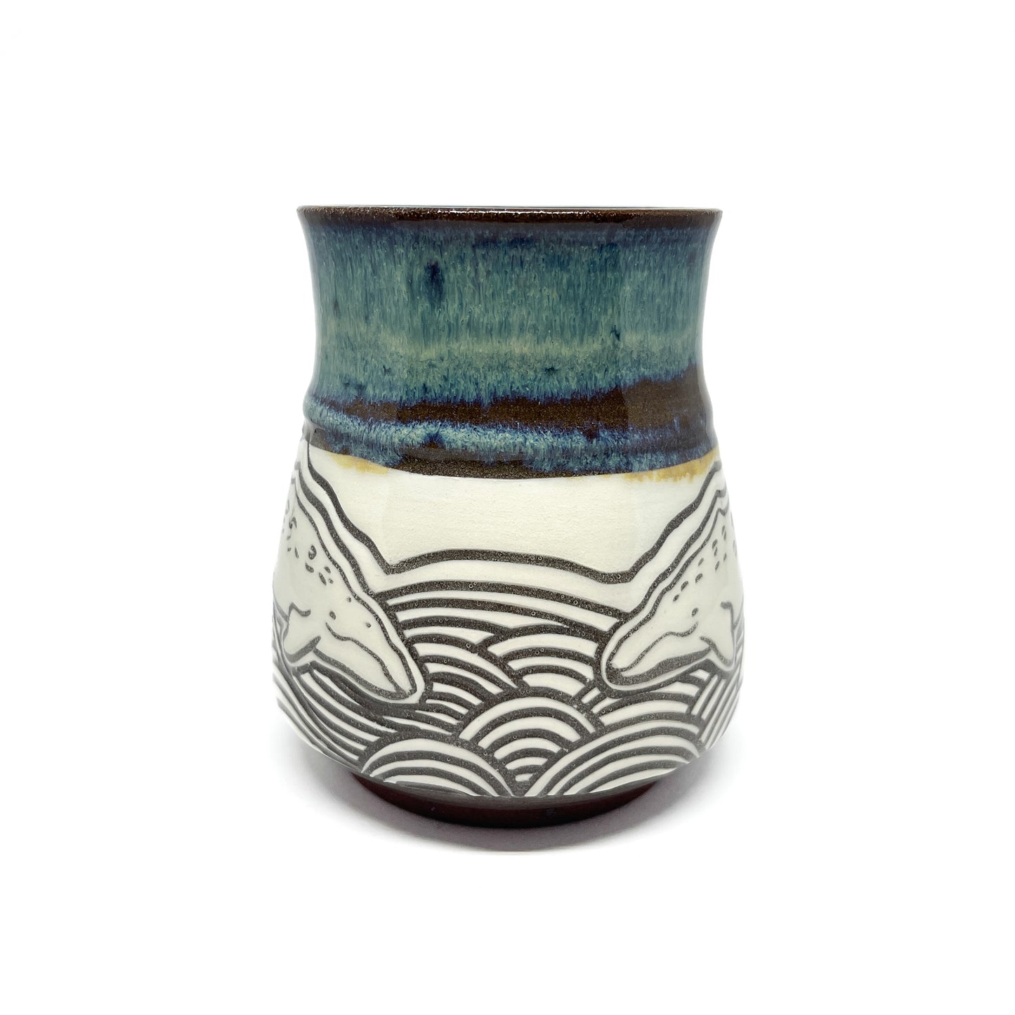 Rear view of mug with two whales facing each other above detailed wave patterns.