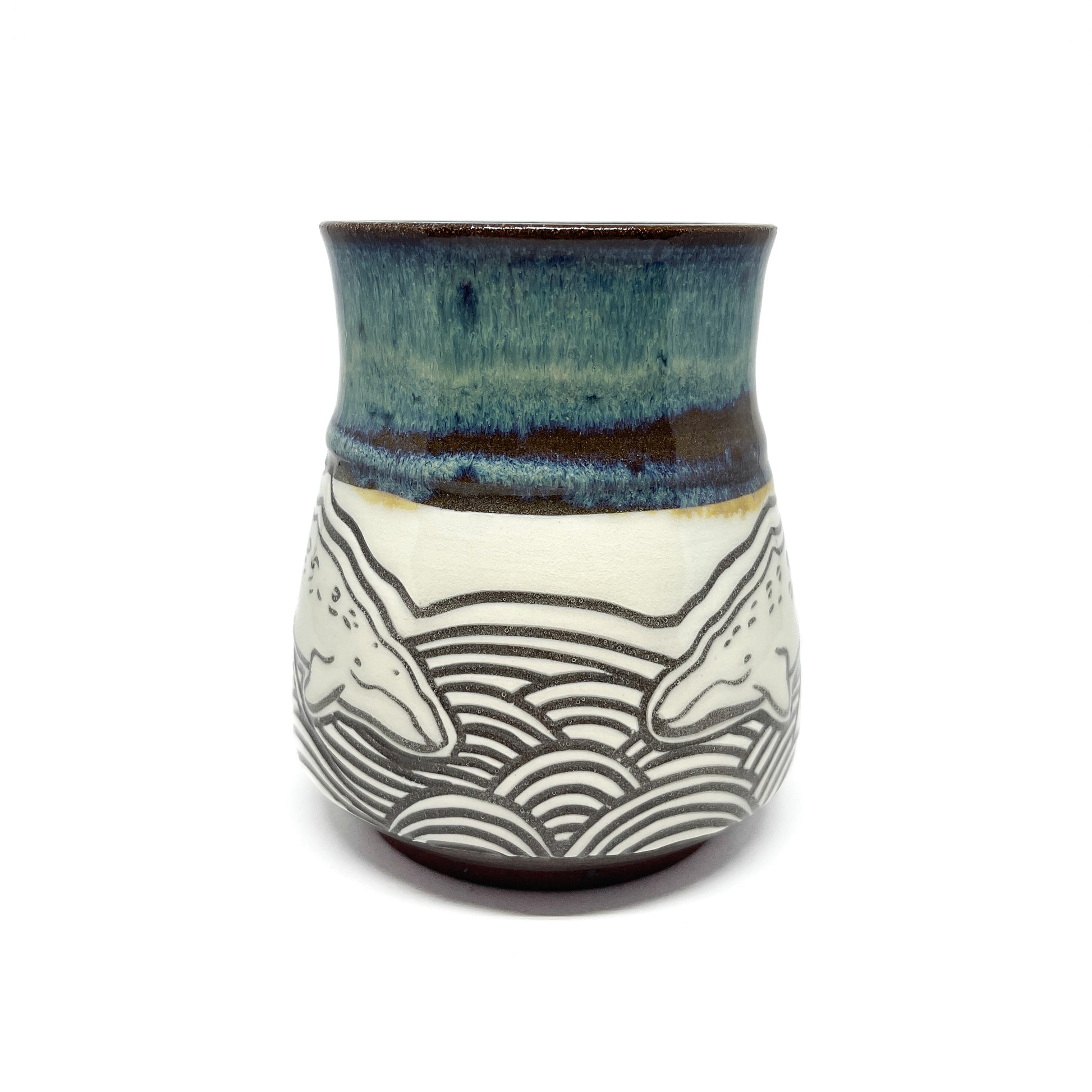 Rear view of mug with two whales facing each other above detailed wave patterns.