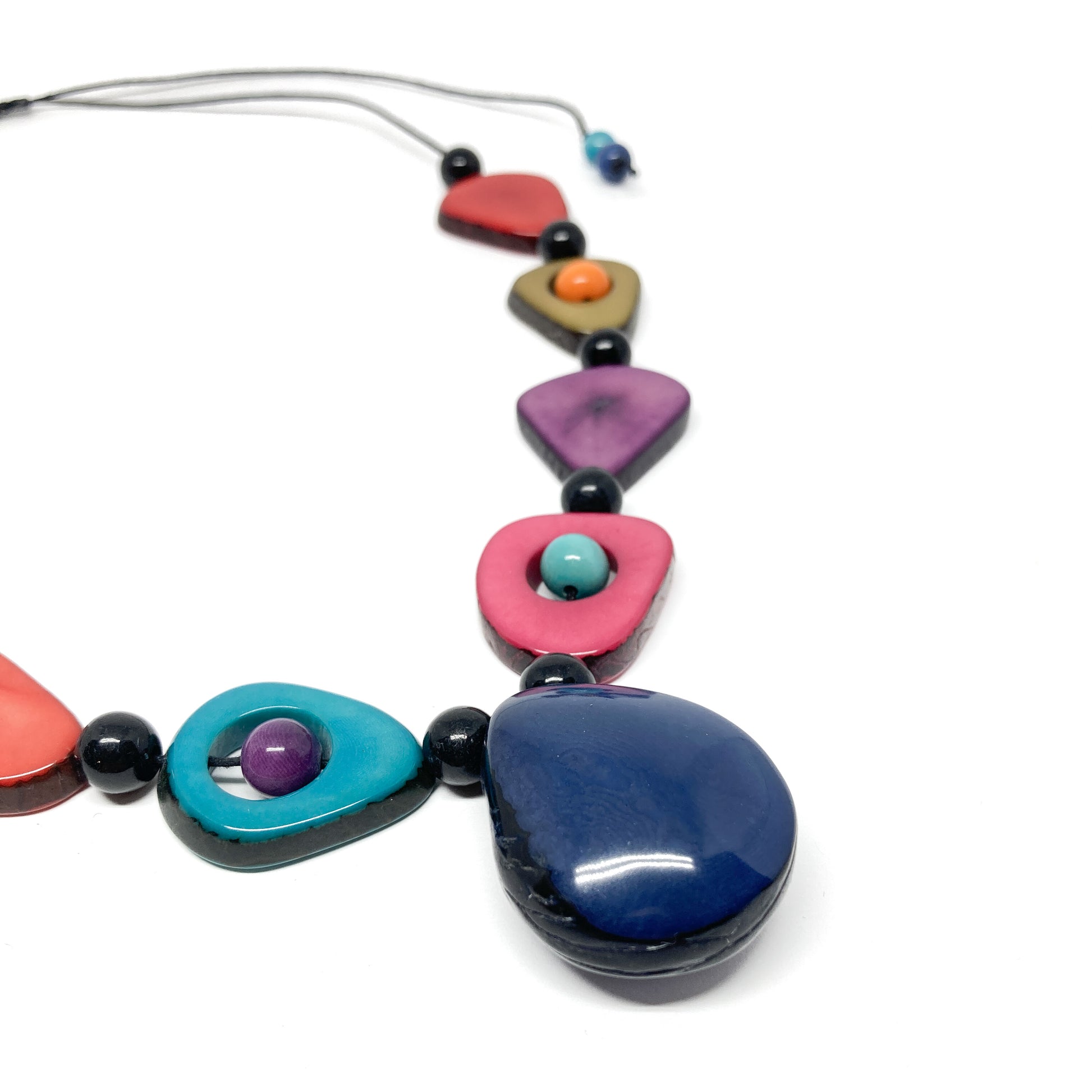 A close-up of a necklace with colorful, irregularly shaped stones and black beads.