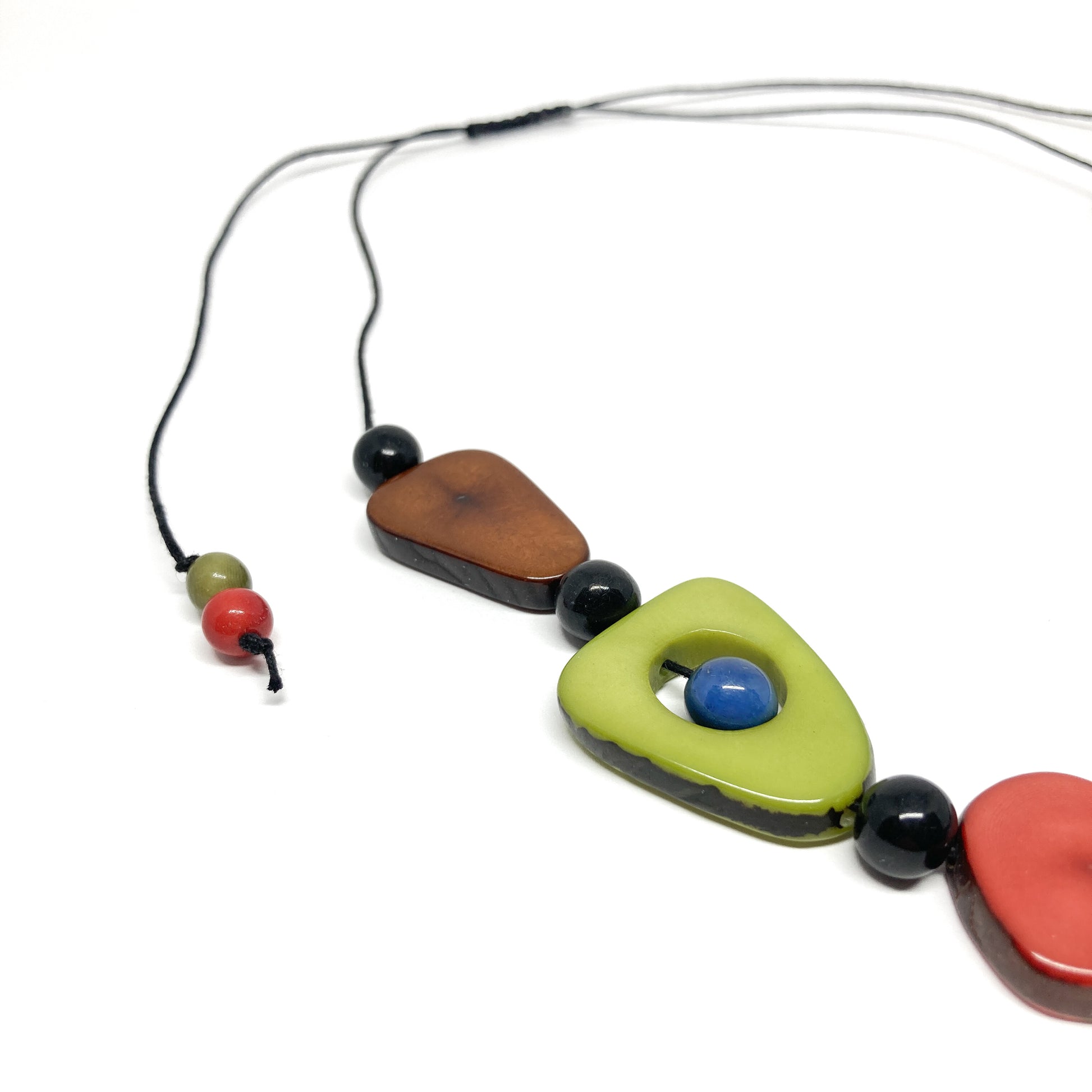 A close-up of a necklace with colorful, irregularly shaped stones and black beads on a thin black cord.