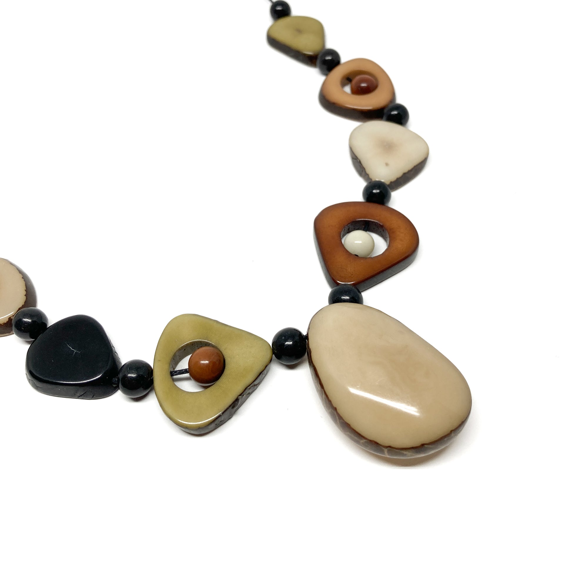 A close-up of a necklace with irregularly shaped, earth-toned stones and black beads.