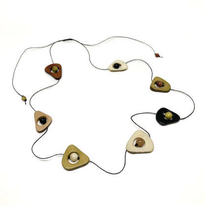 A necklace with earth-toned stones and black beads on a thin black cord, laid flat in a circular pattern.