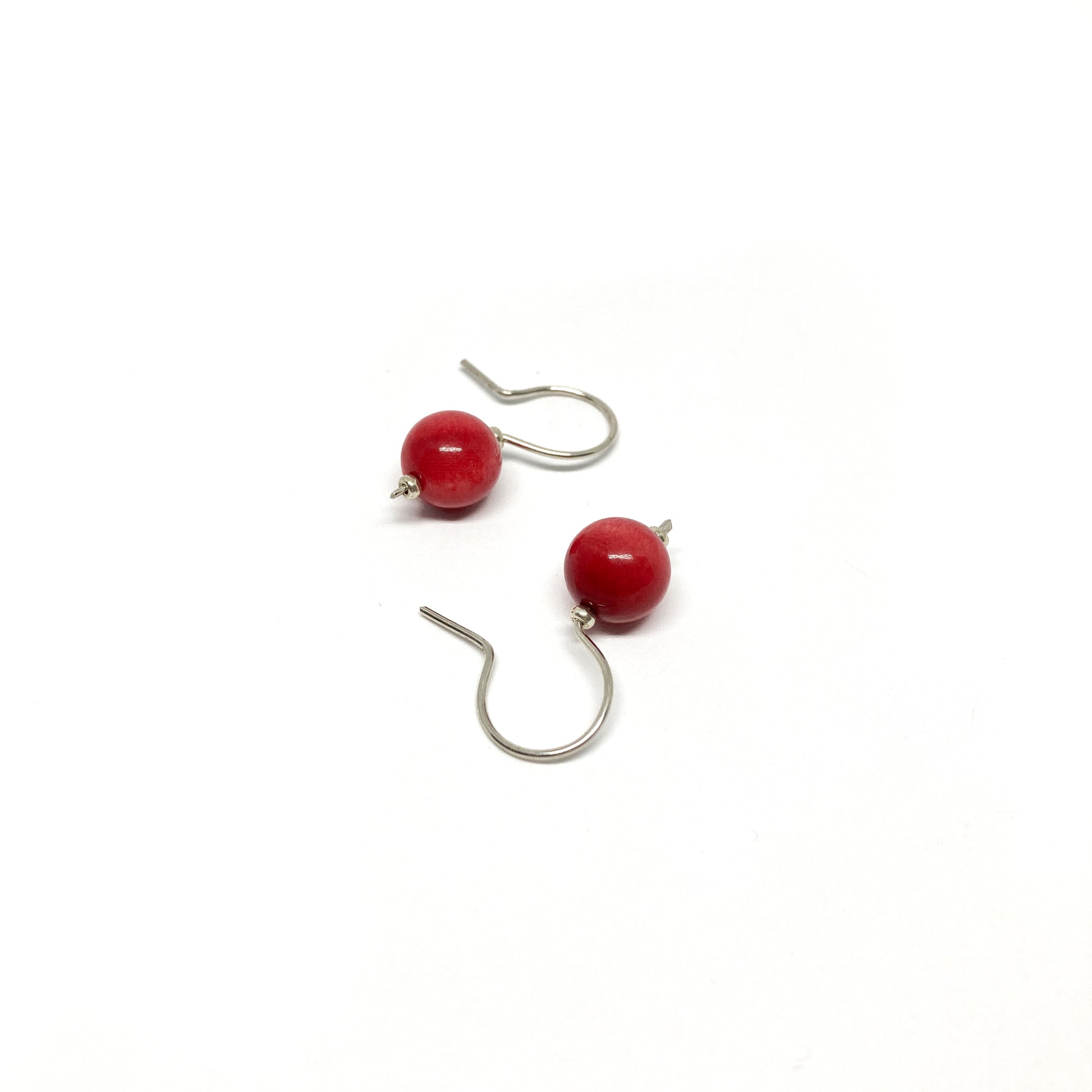 Two red pearl earrings with silver hooks.