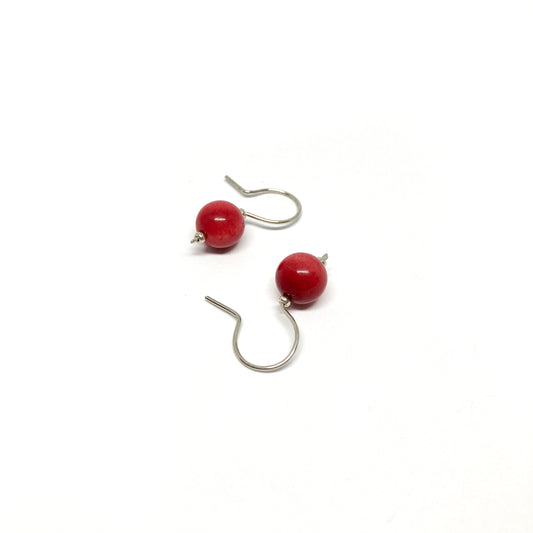 Two red pearl earrings with silver hooks.