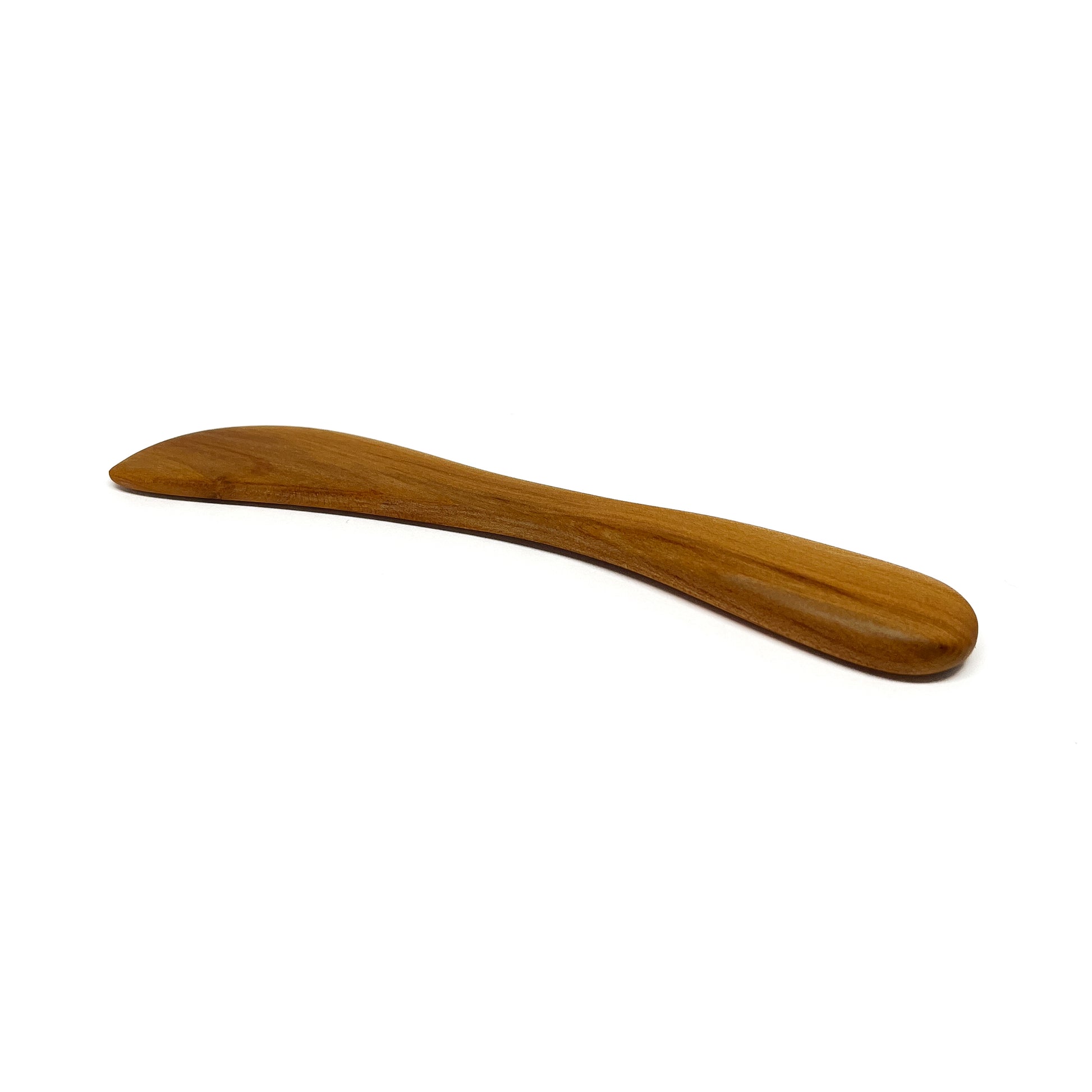 A wooden spread knife, angled on a white surface.