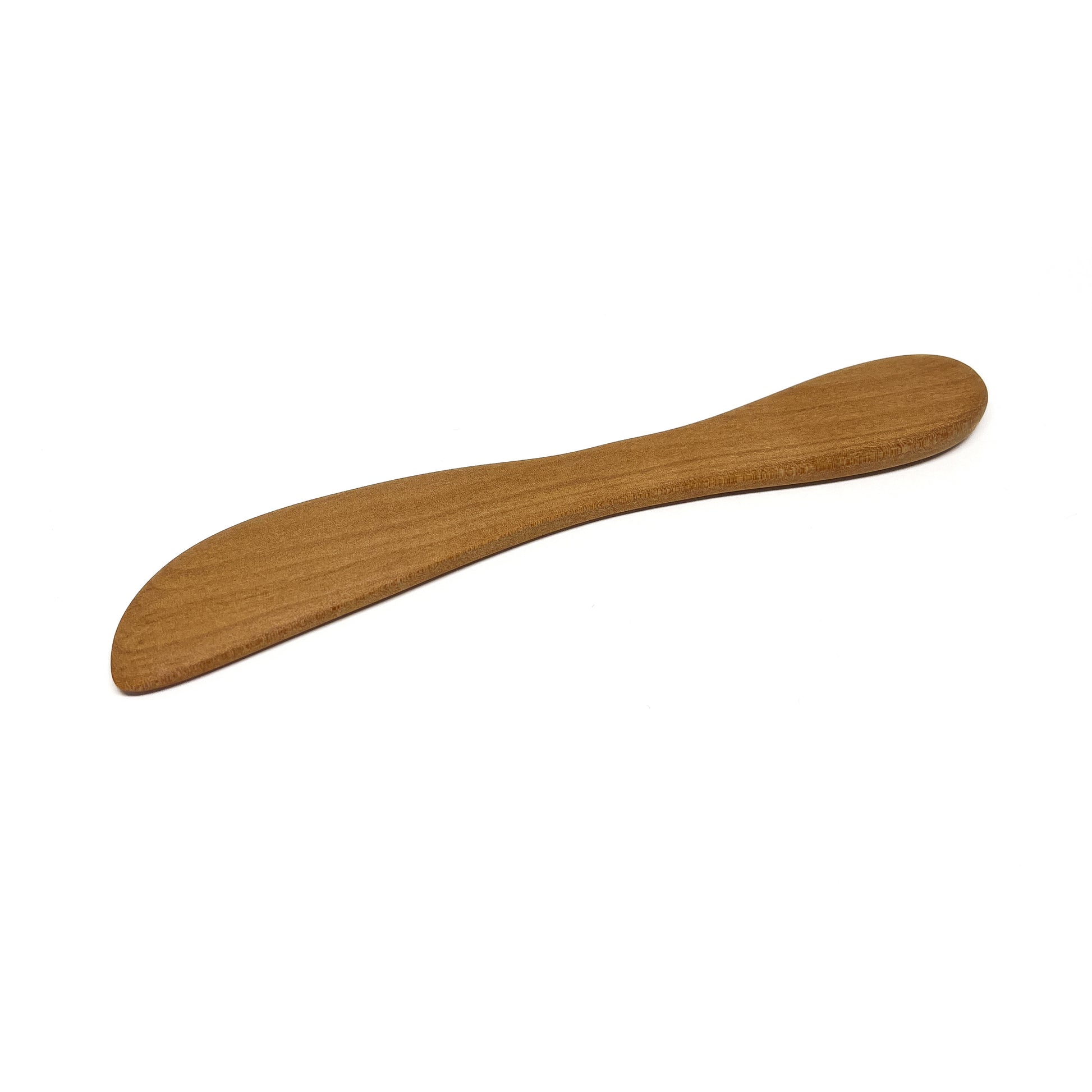 A wooden spread knife, angled on a white surface.