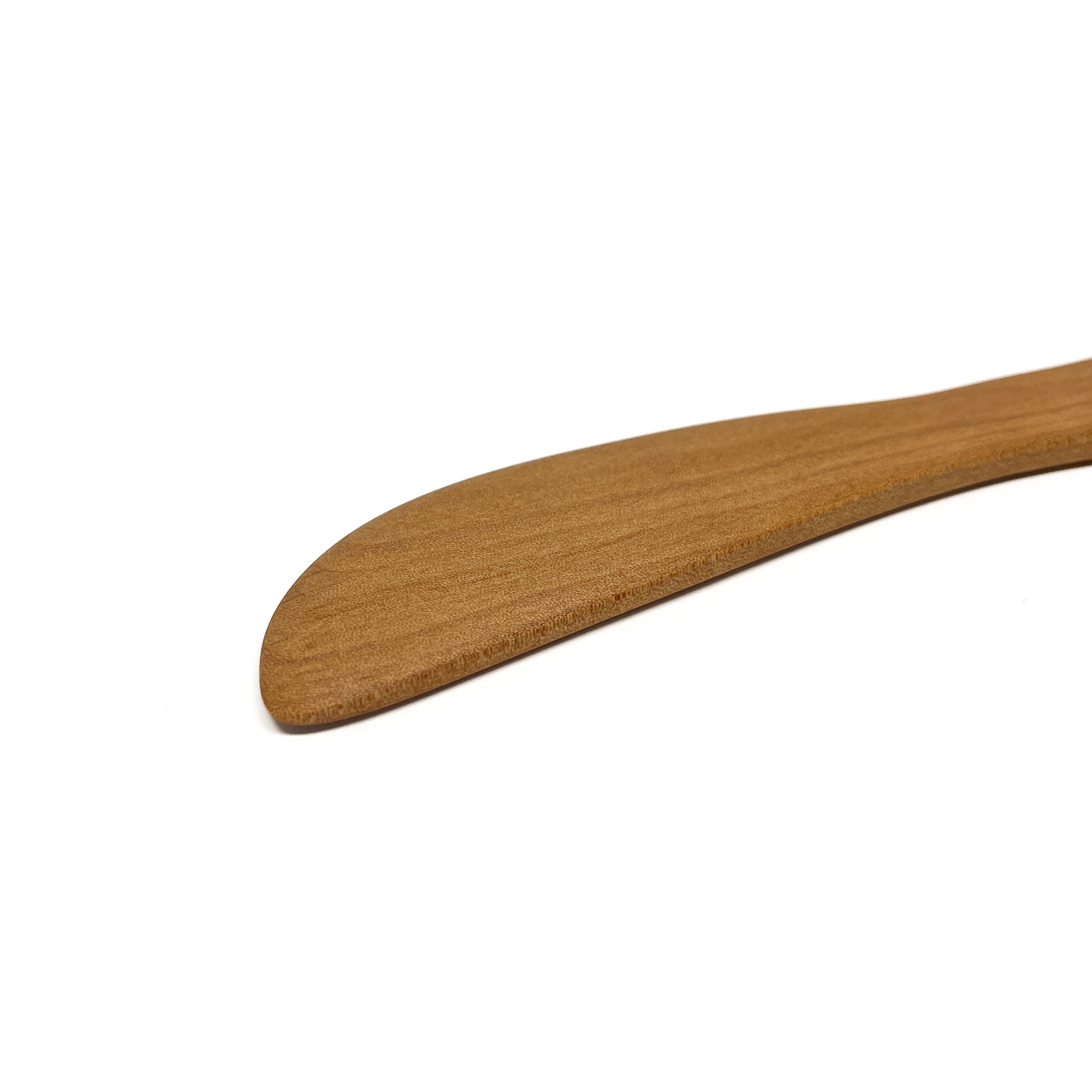 Close-up of a wooden spread knife tip, angled on a white surface.
