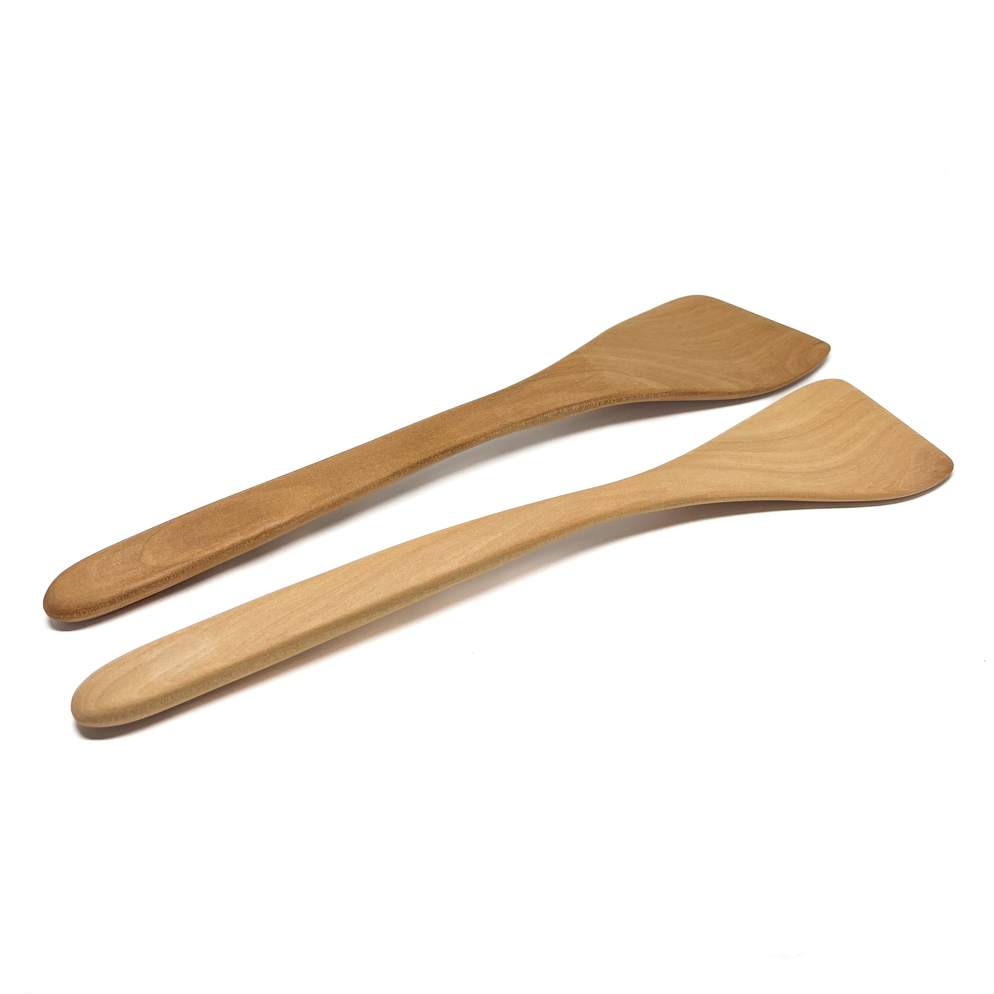 Two wooden spatulas in varying shades, angled on a white surface.