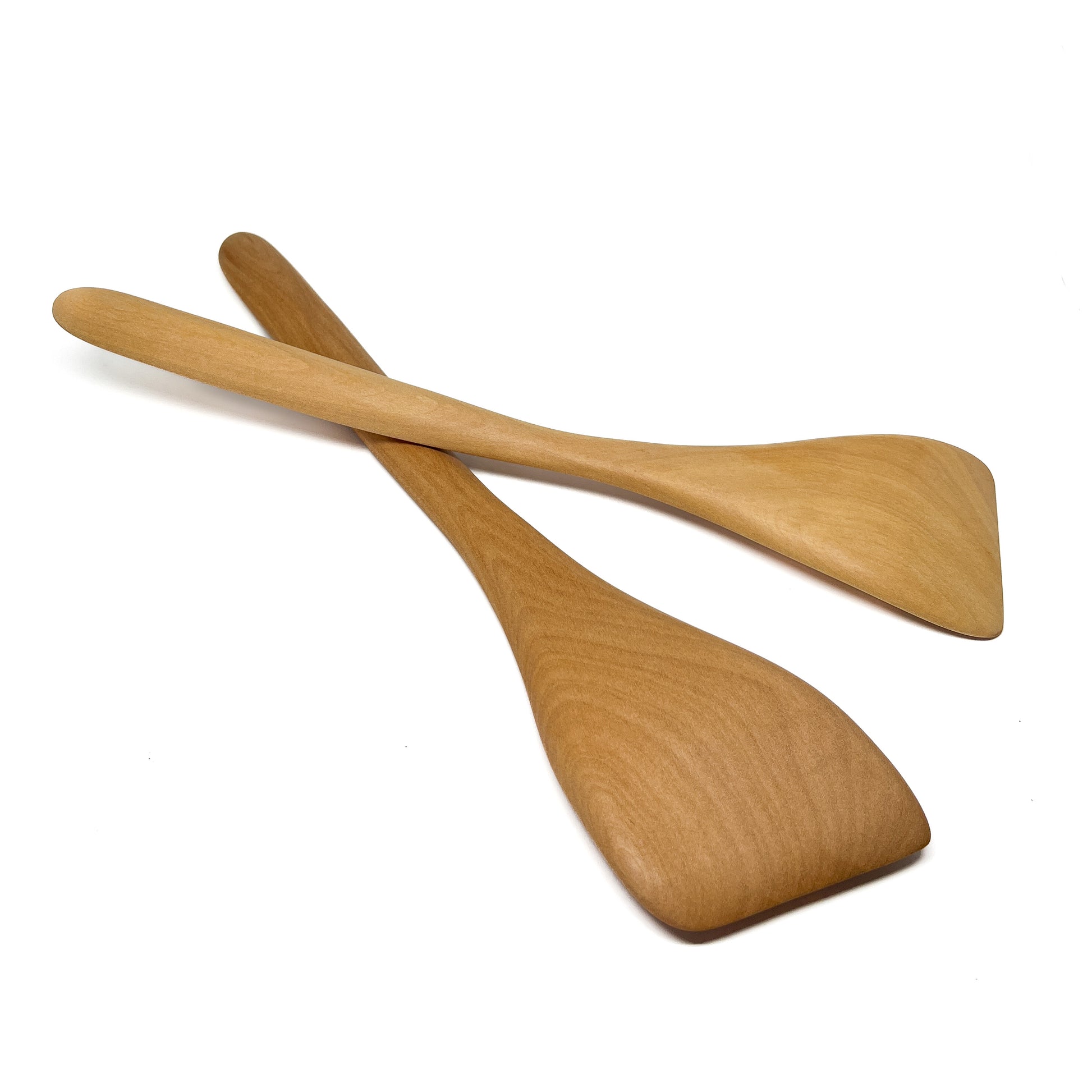 Two wooden spatulas crossed on a white surface.