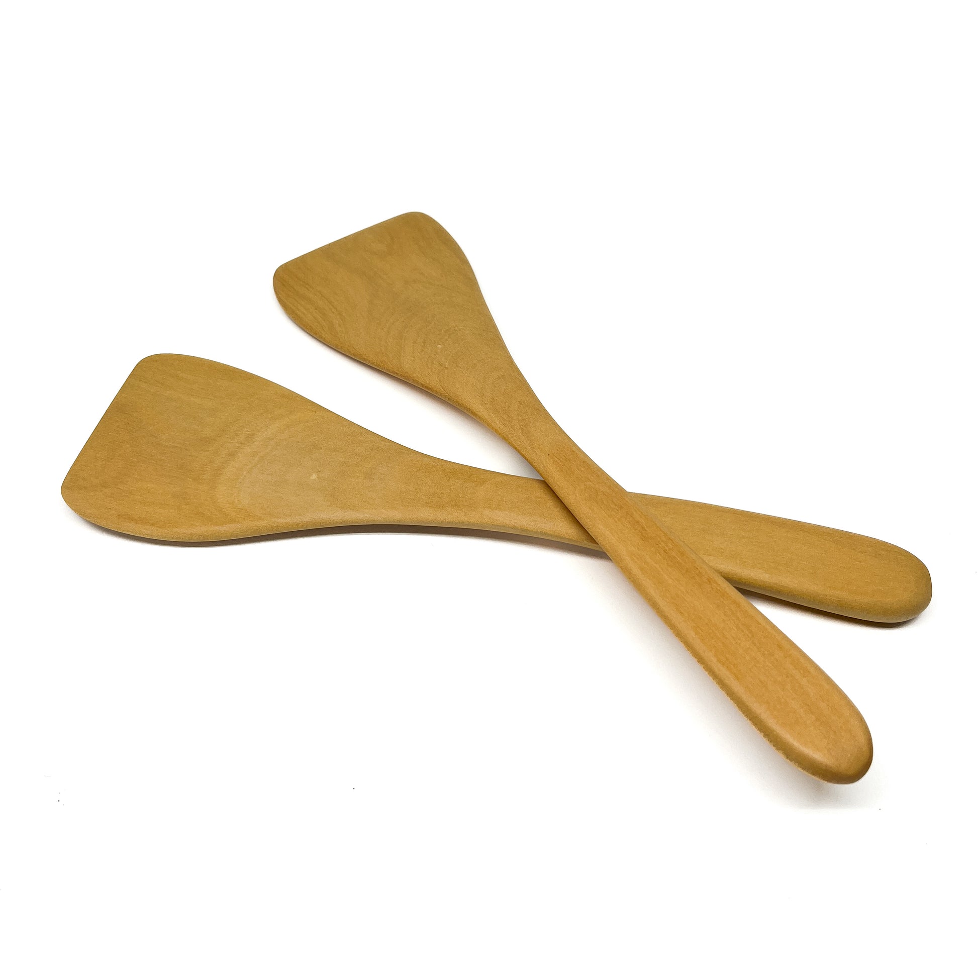 Two wooden spatulas crossed on a white surface.