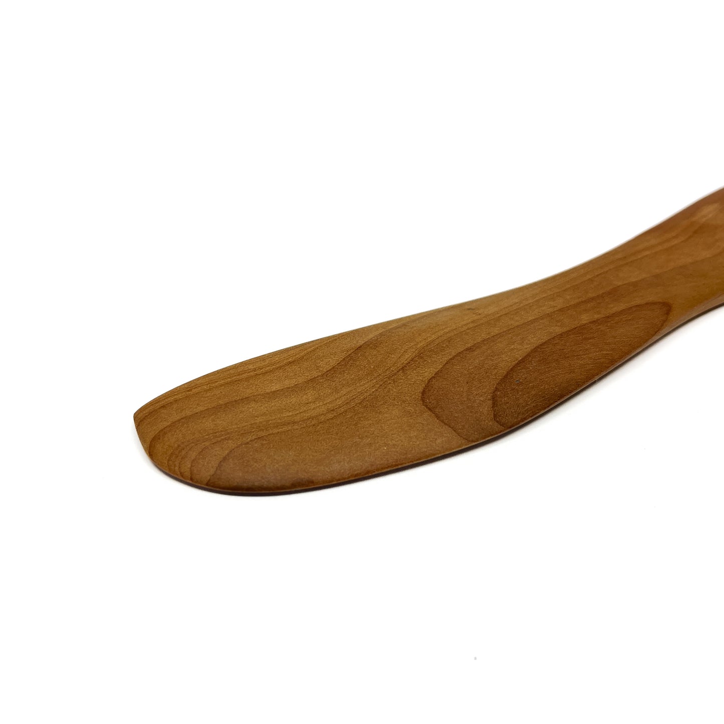 Close-up of a wooden spread knife tip, angled on a white surface.