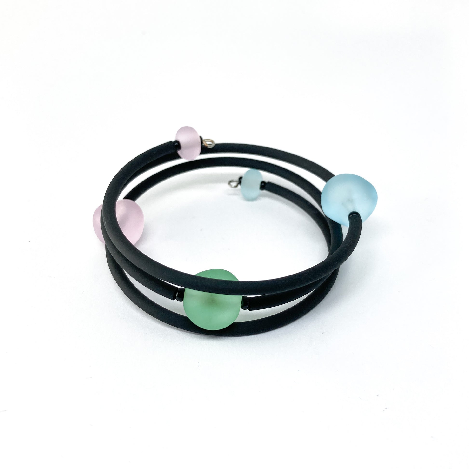 Black rubber bracelet with pink, light blue, and green beads.
