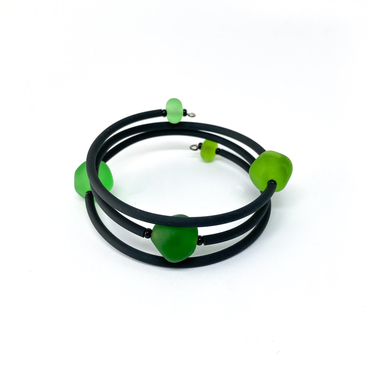 Black rubber bracelet with green beads.