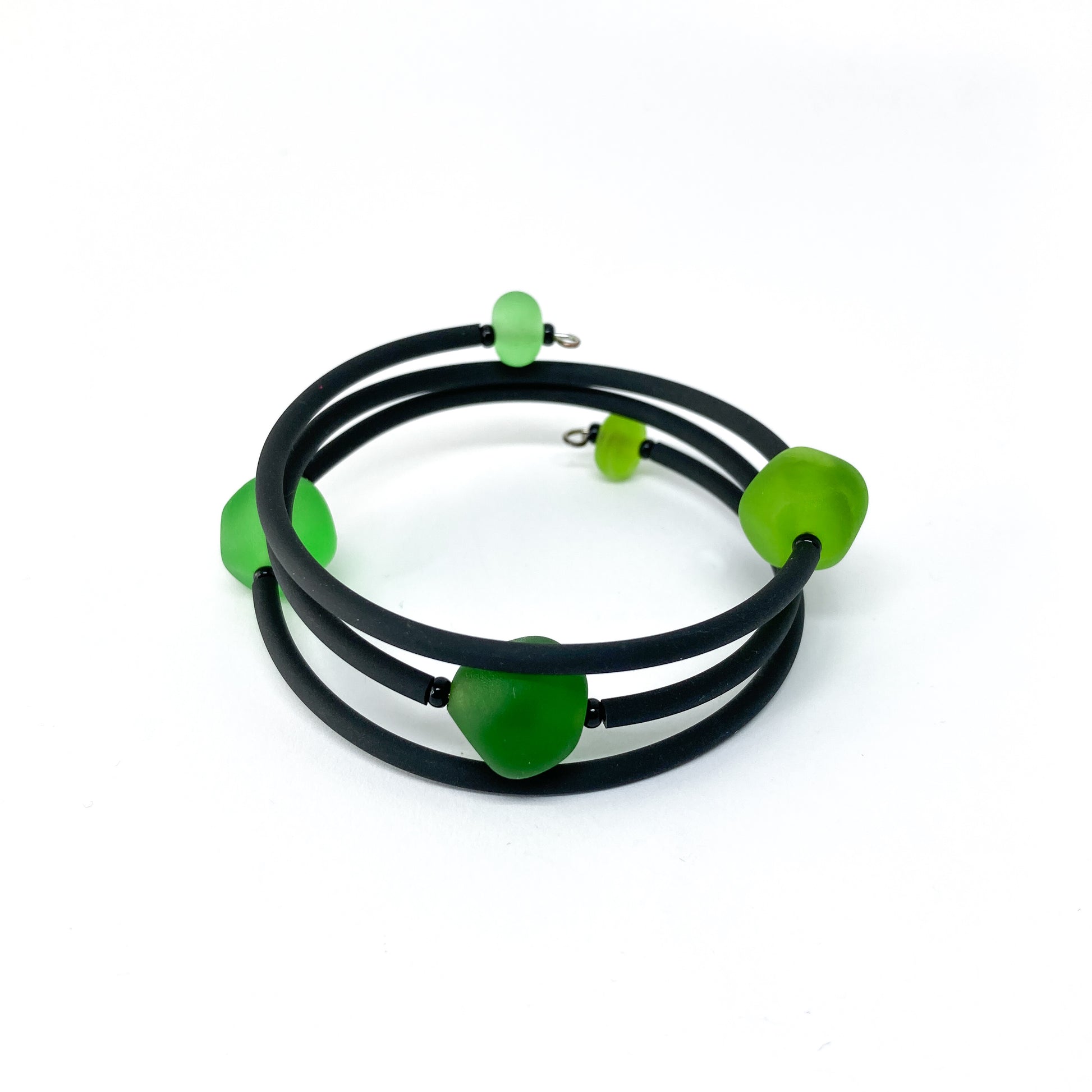 Black rubber bracelet with green beads.