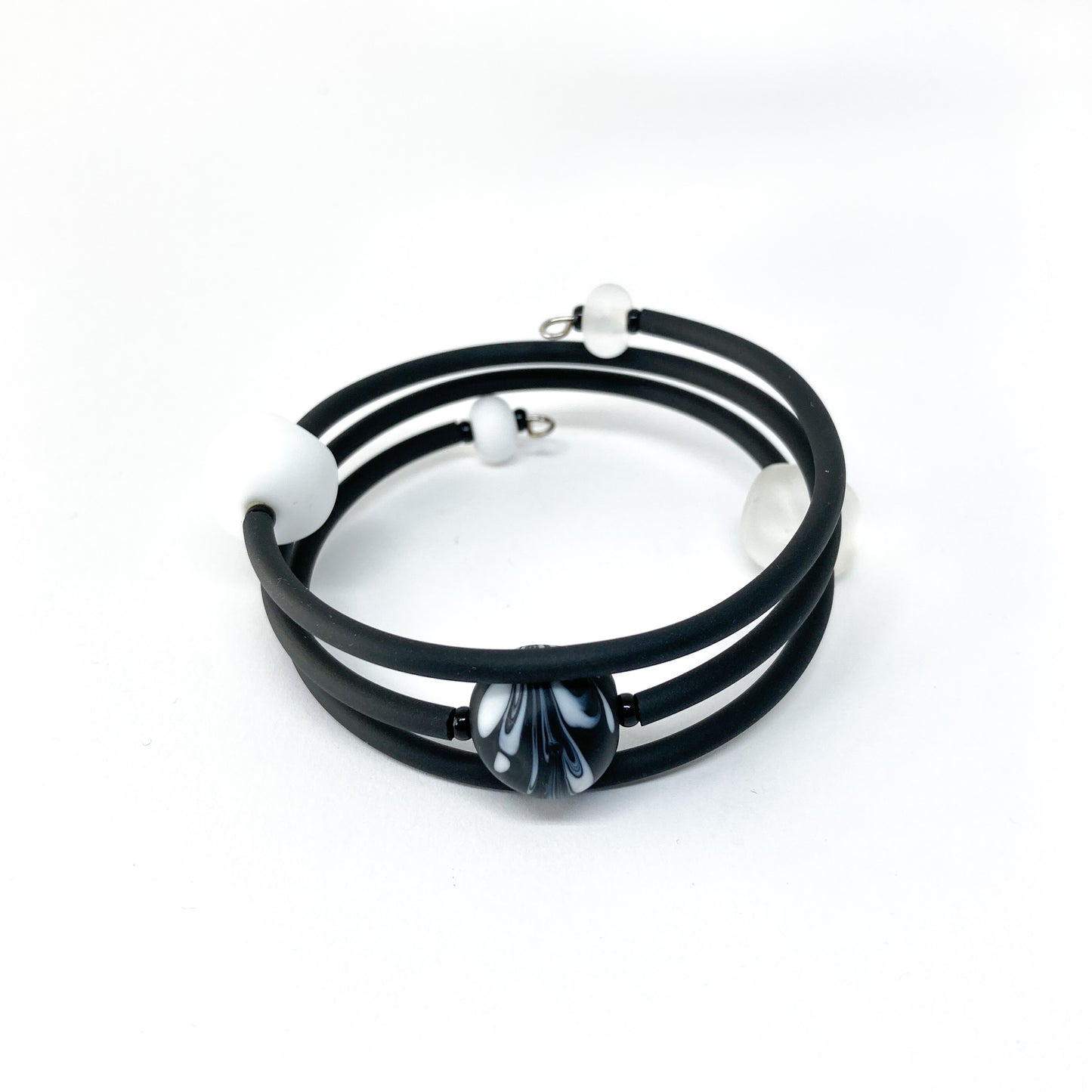 Black rubber bracelet with white and black patterned beads.